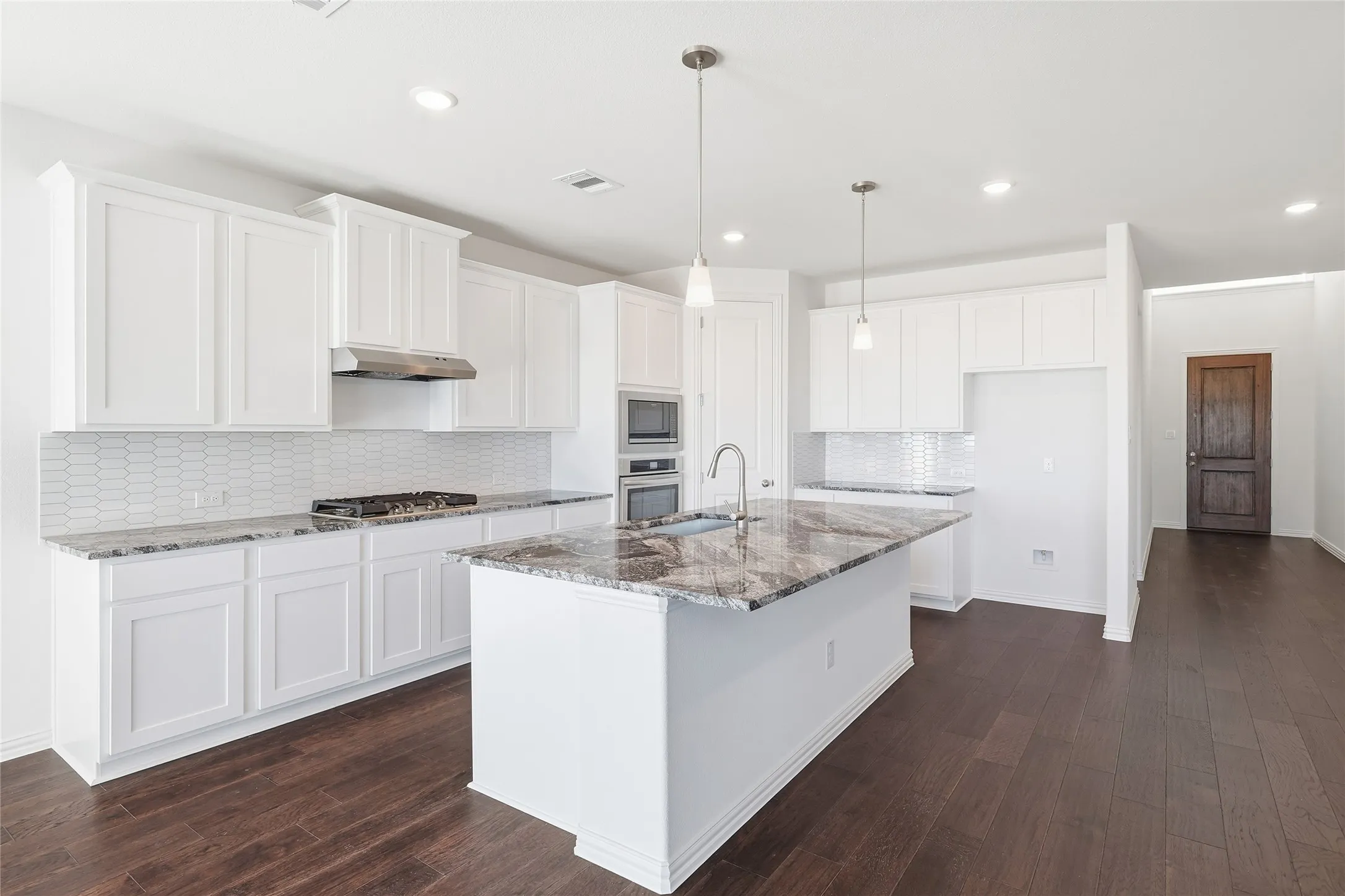 Modern kitchen featuring white shaker cabinetry and a large island with a stone countertop