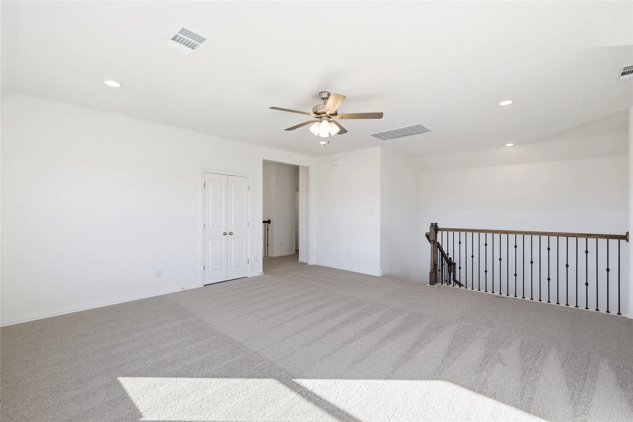 Spacious carpeted room featuring a ceiling fan, recessed lighting, and a double-door closet