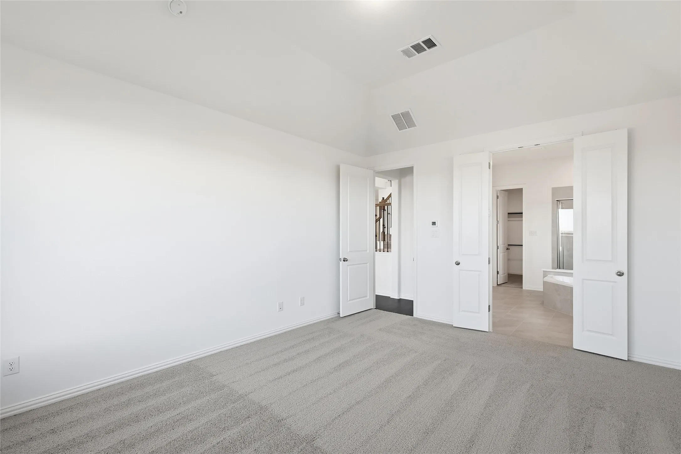 Spacious room featuring vaulted ceilings, light gray carpeting, and two sets of double doors