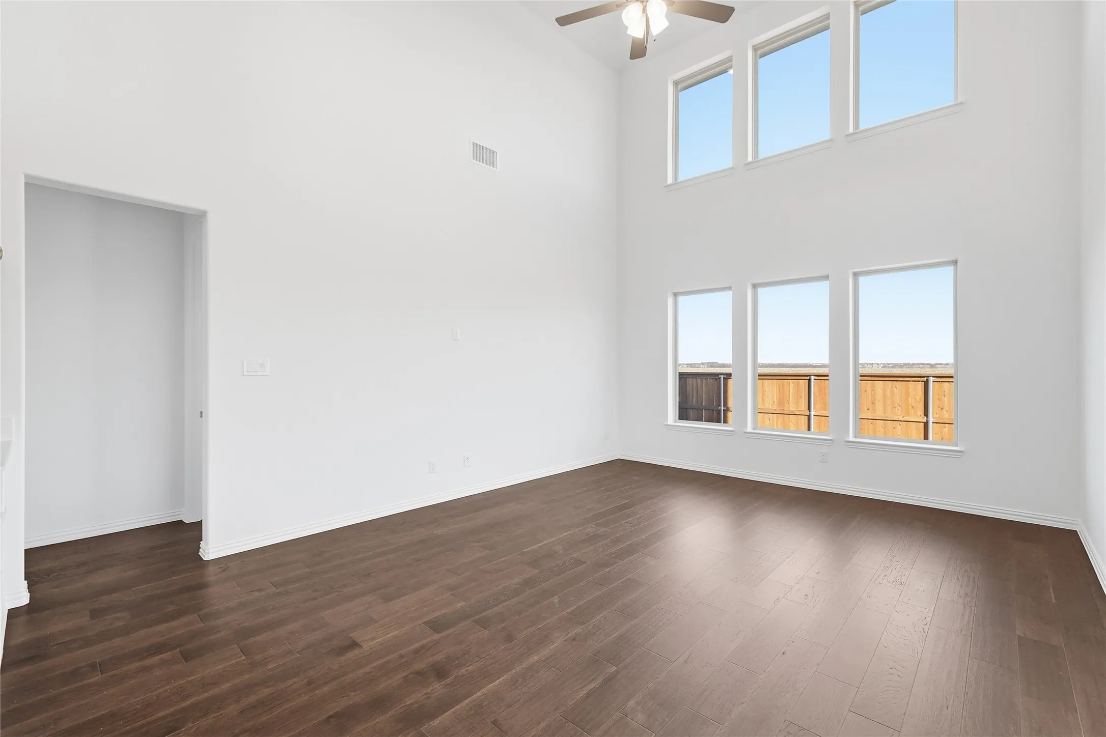Expansive room featuring high ceilings, dark wood-finish flooring, and multiple large windows