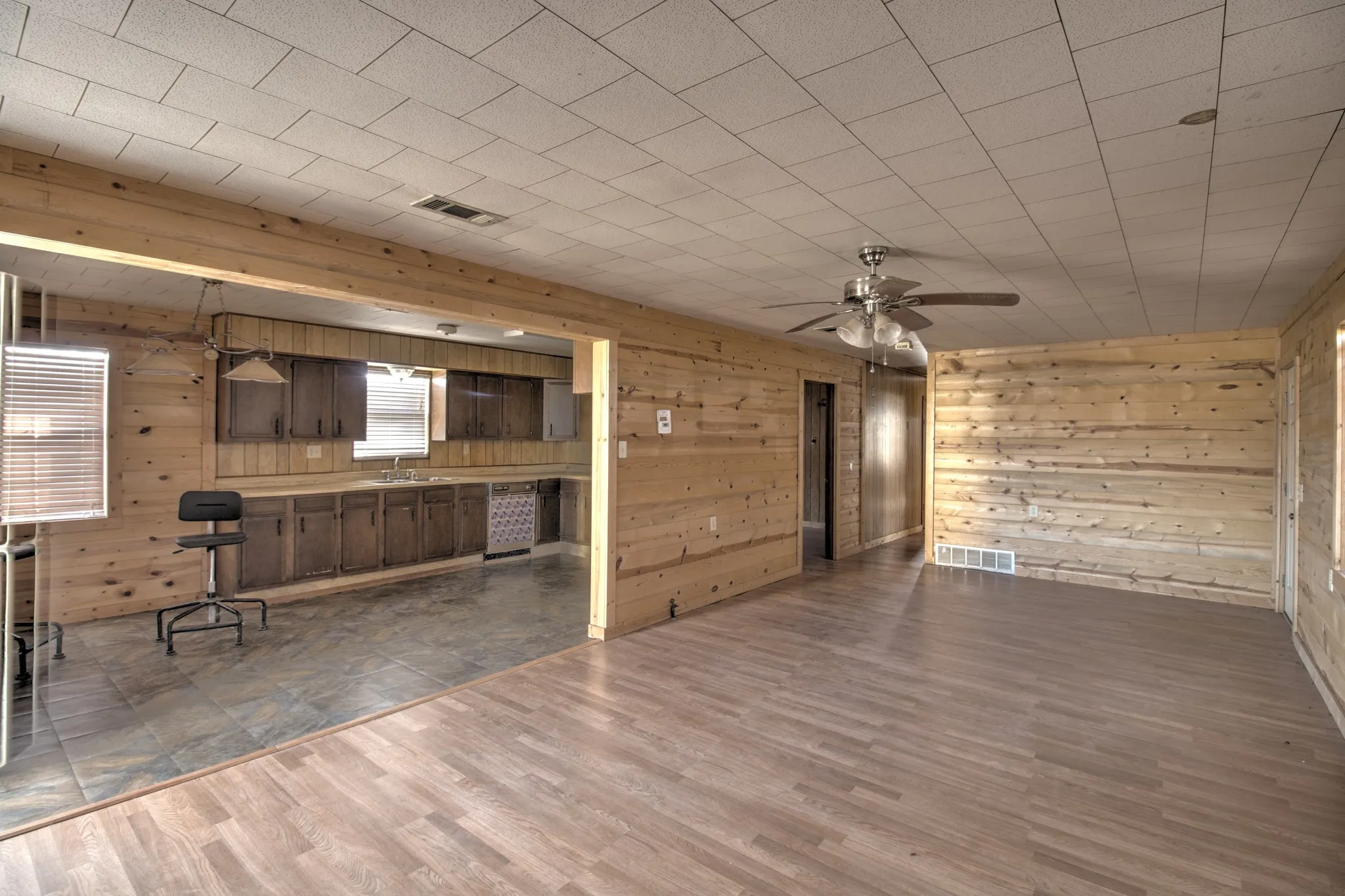 Unfurnished living room with dark wood-style floors, ceiling fan, and wooden walls