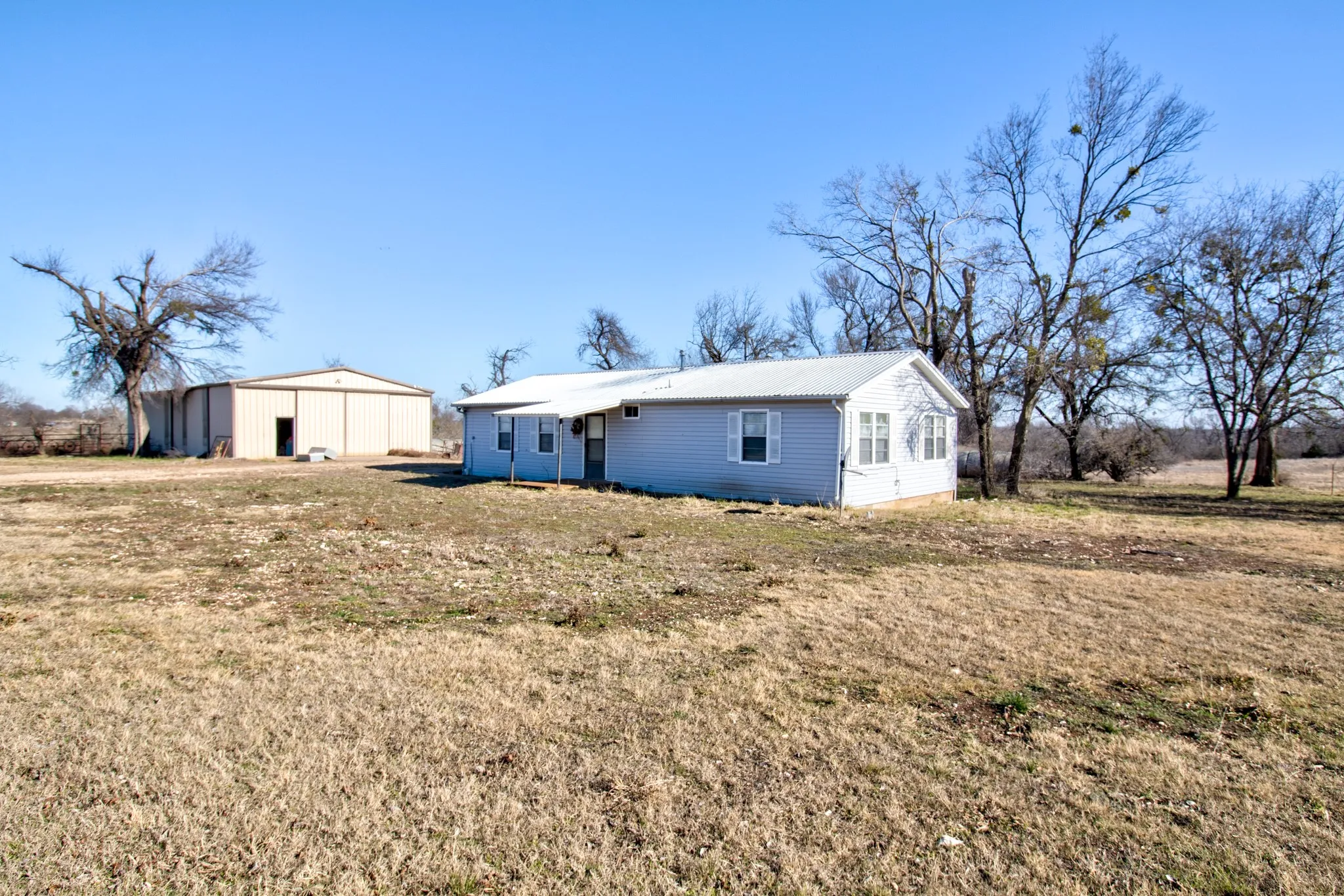 Back of house with an outdoor structure, a yard, and an outbuilding