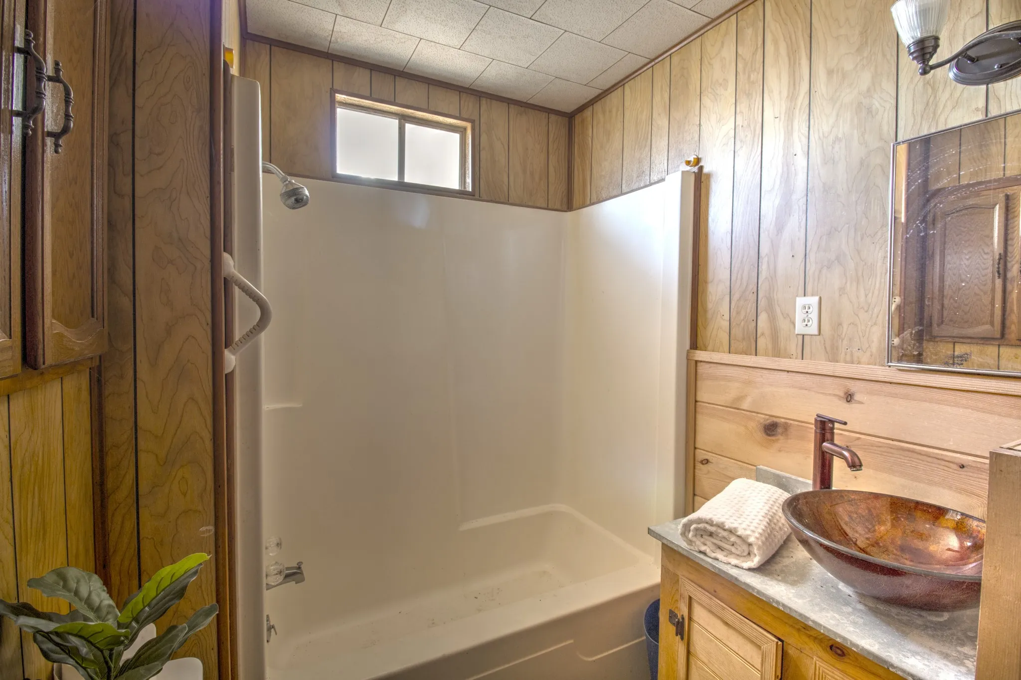 Full bathroom with wood walls, vanity, and shower / washtub combination
