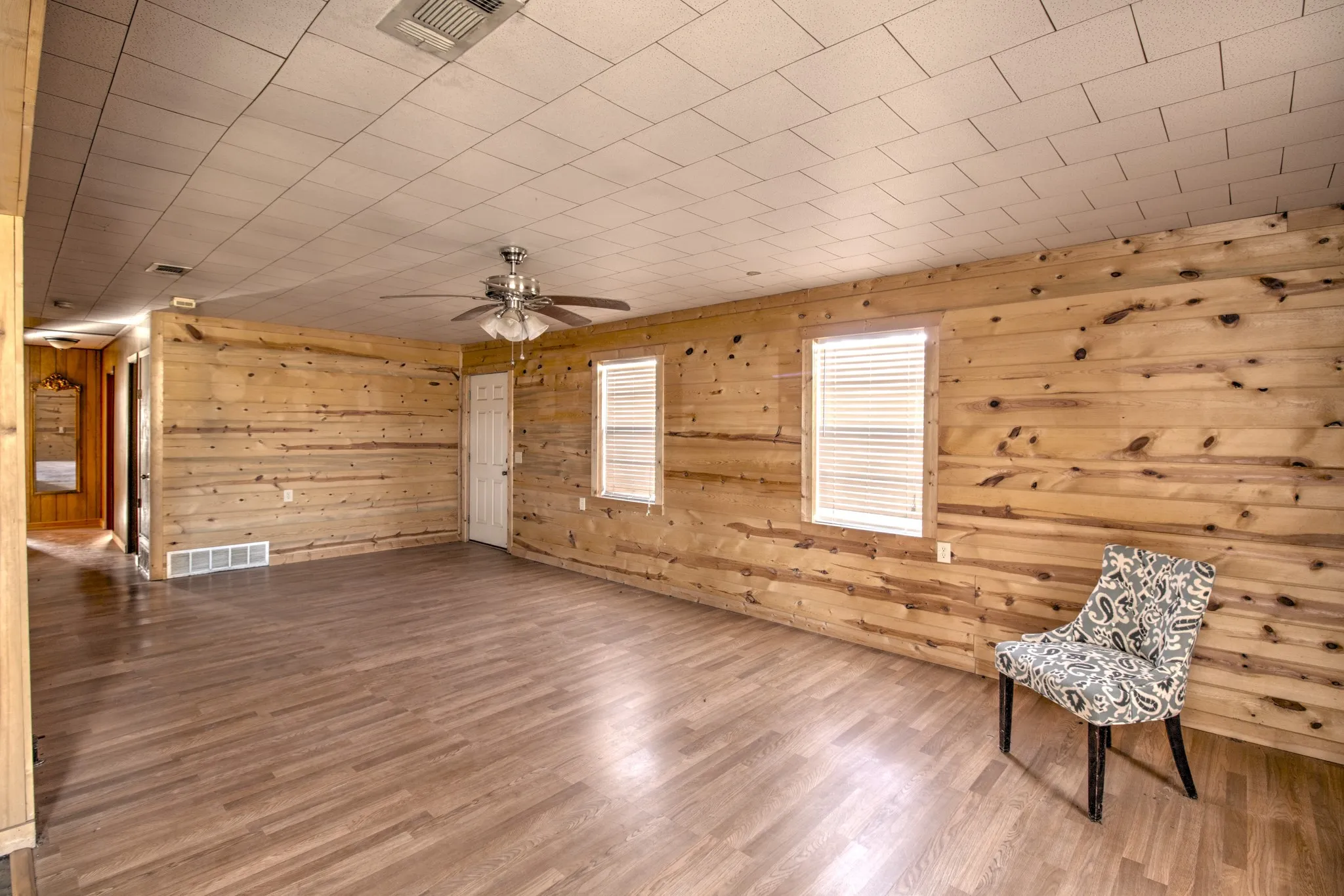 Unfurnished room featuring wood finished floors, wooden walls, and ceiling fan
