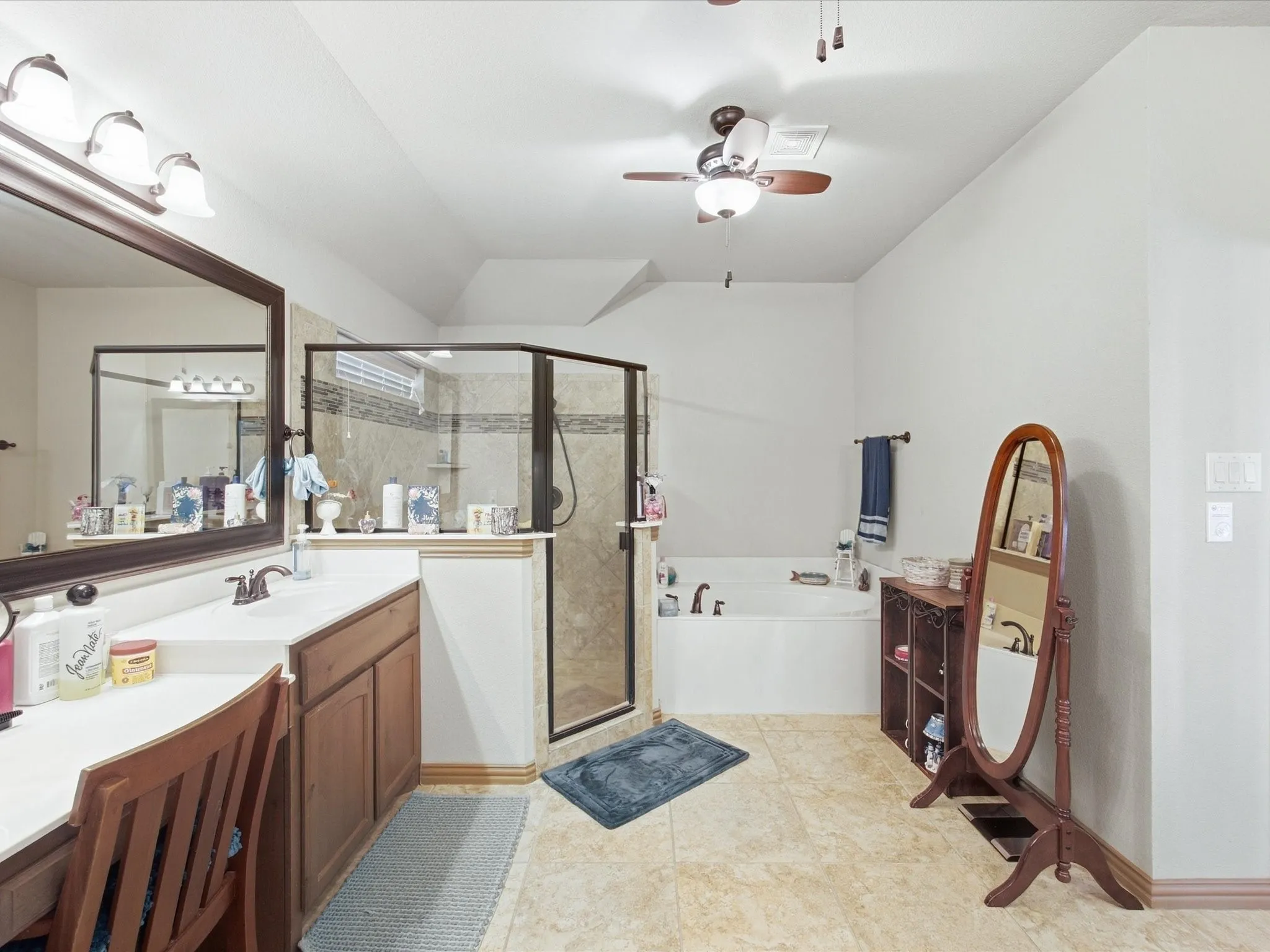 Enclosed glass shower with tiled surround, separate soaking tub, double vanity with integrated sink, wood-finish cabinetry, and tiled flooring