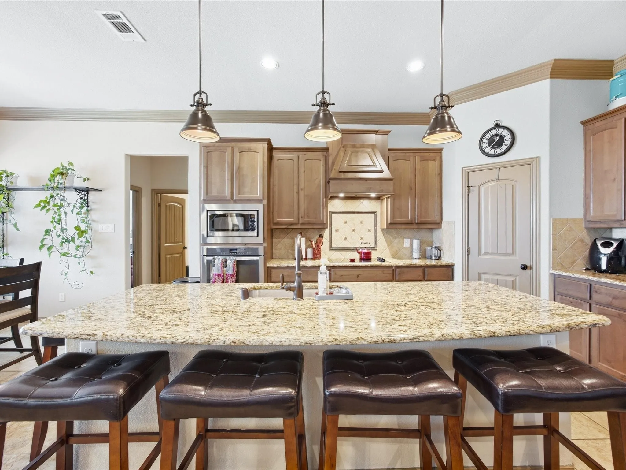 Kitchen featuring a large island with granite countertops, wood cabinetry, stainless steel appliances, and pendant lighting