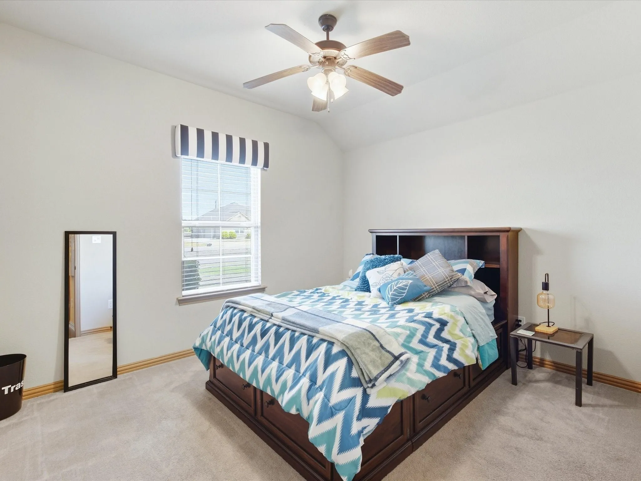 Neutral-toned walls, vaulted ceiling with a ceiling fan, window with blinds, and light-colored carpet