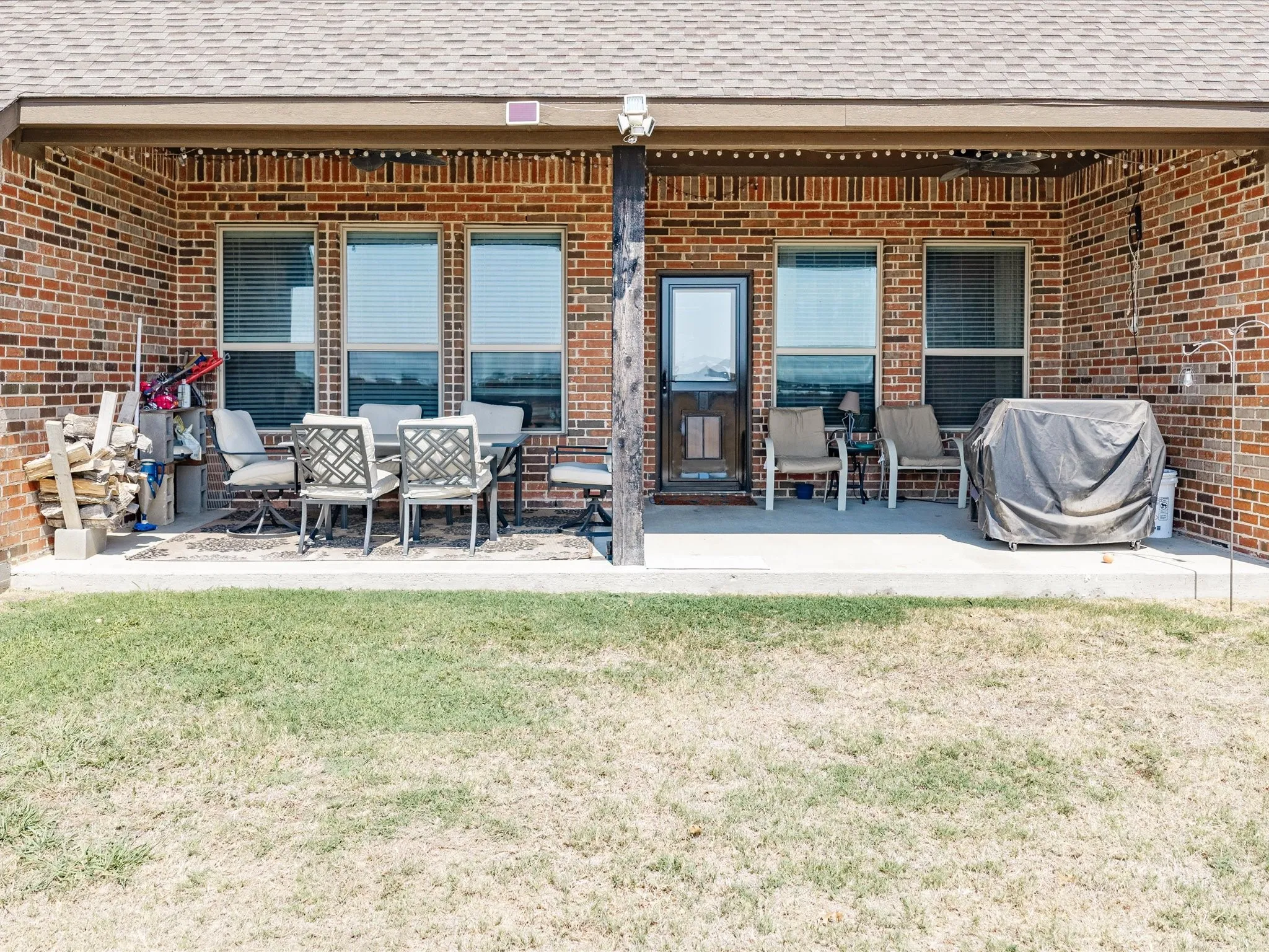 Covered patio with a concrete surface, brick exterior, and multiple windows
