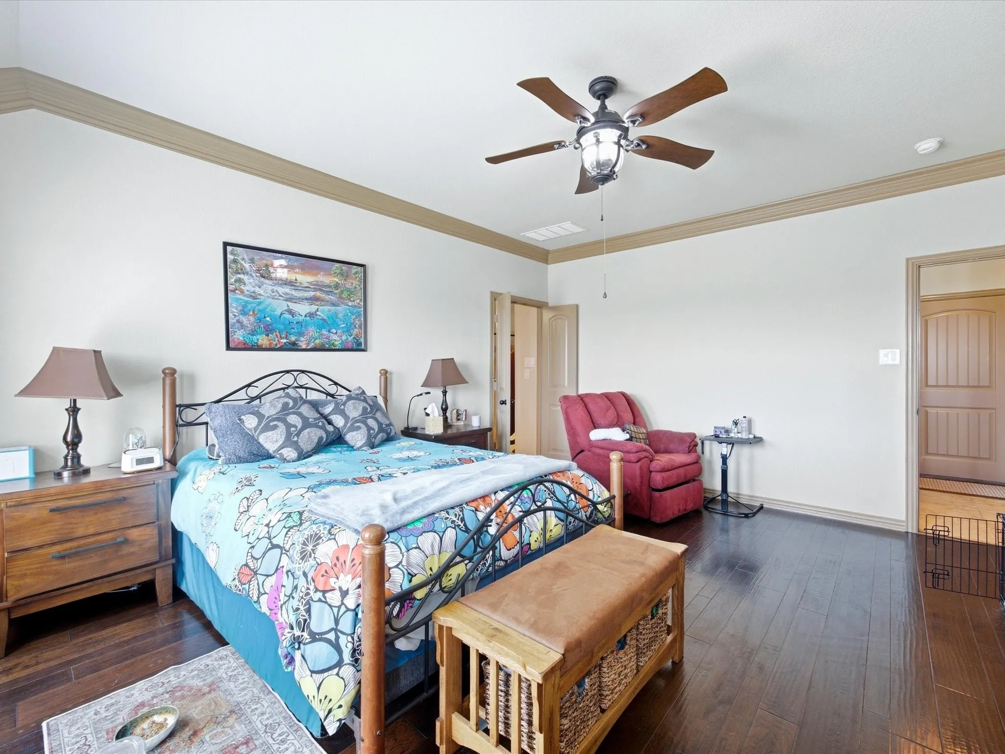 Hardwood-finish flooring, crown molding, ceiling fan with integrated lighting, and a paneled door