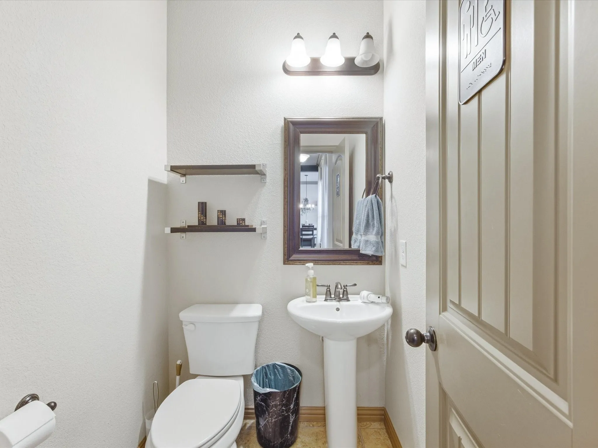 Pedestal sink with chrome faucet, framed mirror, and beadboard panel door