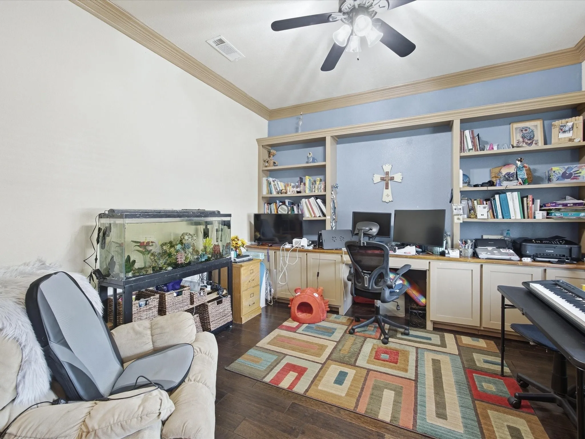 Wood-finish flooring, built-in shelving, crown molding, and a ceiling fan with integrated lighting