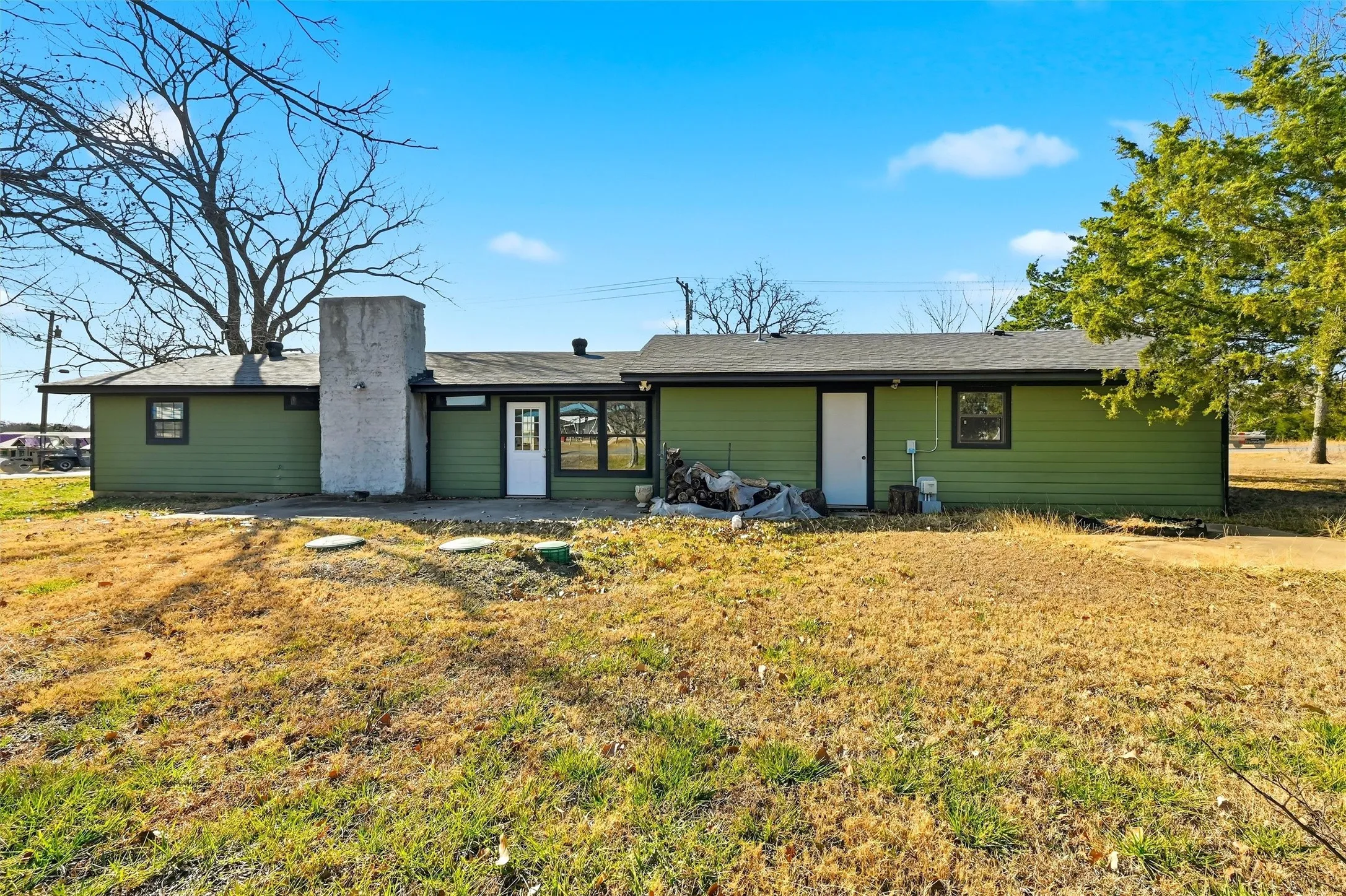Back of property with a chimney, a lawn, and a patio
