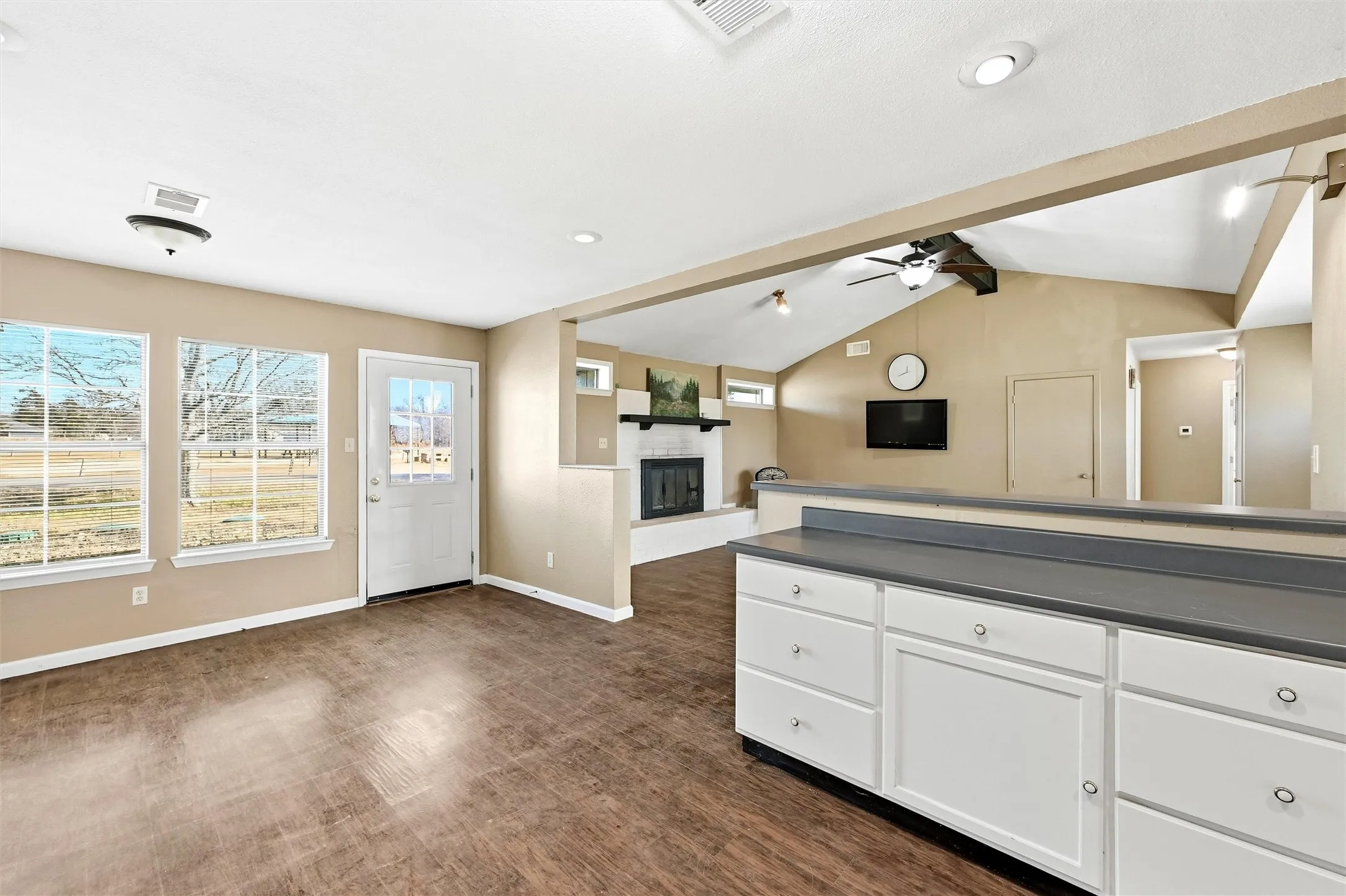 Kitchen featuring dark countertops, white cabinetry, a fireplace with raised hearth, open floor plan, and dark wood-style floors