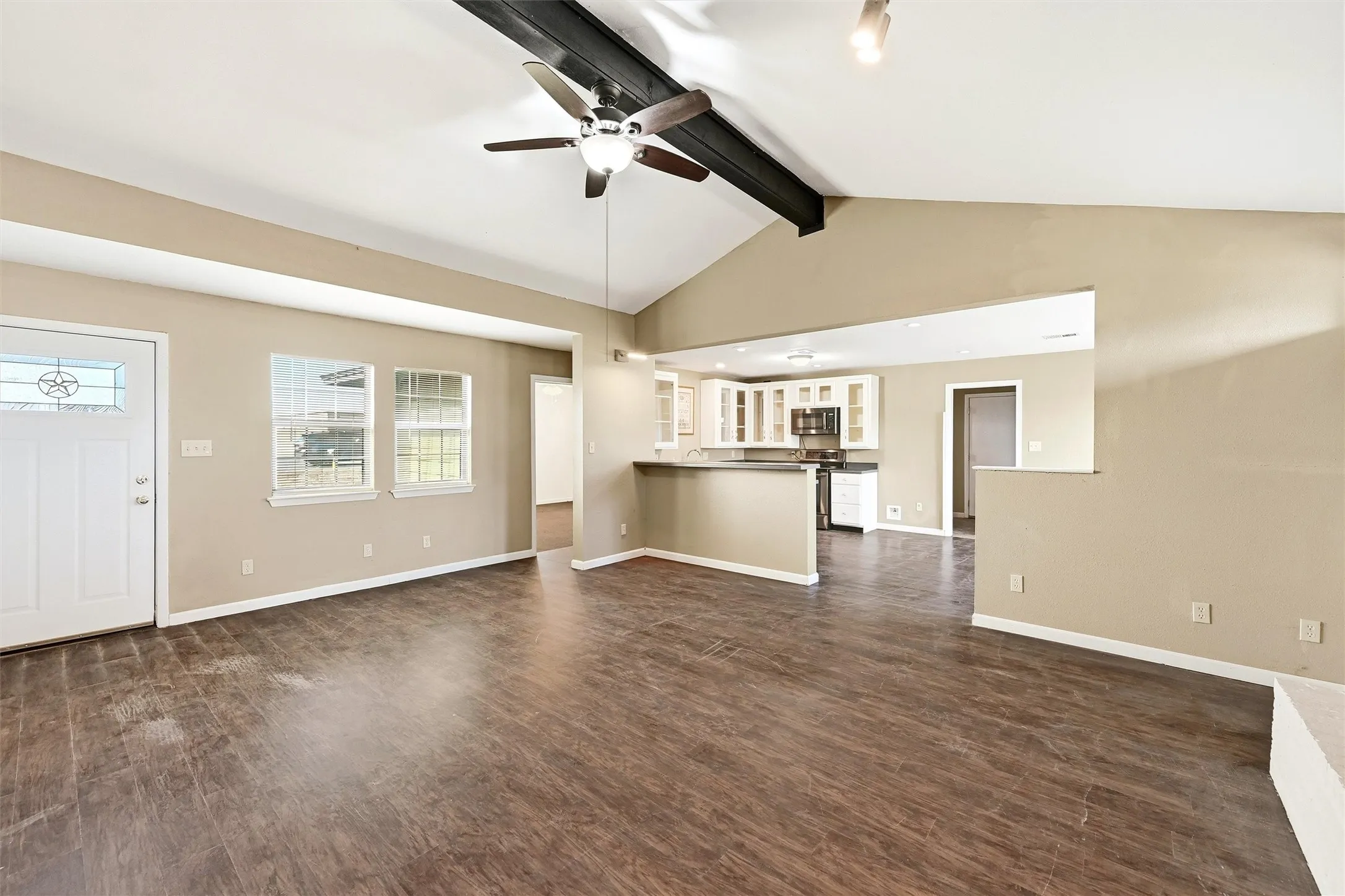 Unfurnished living room featuring ceiling fan and dark wood-type flooring