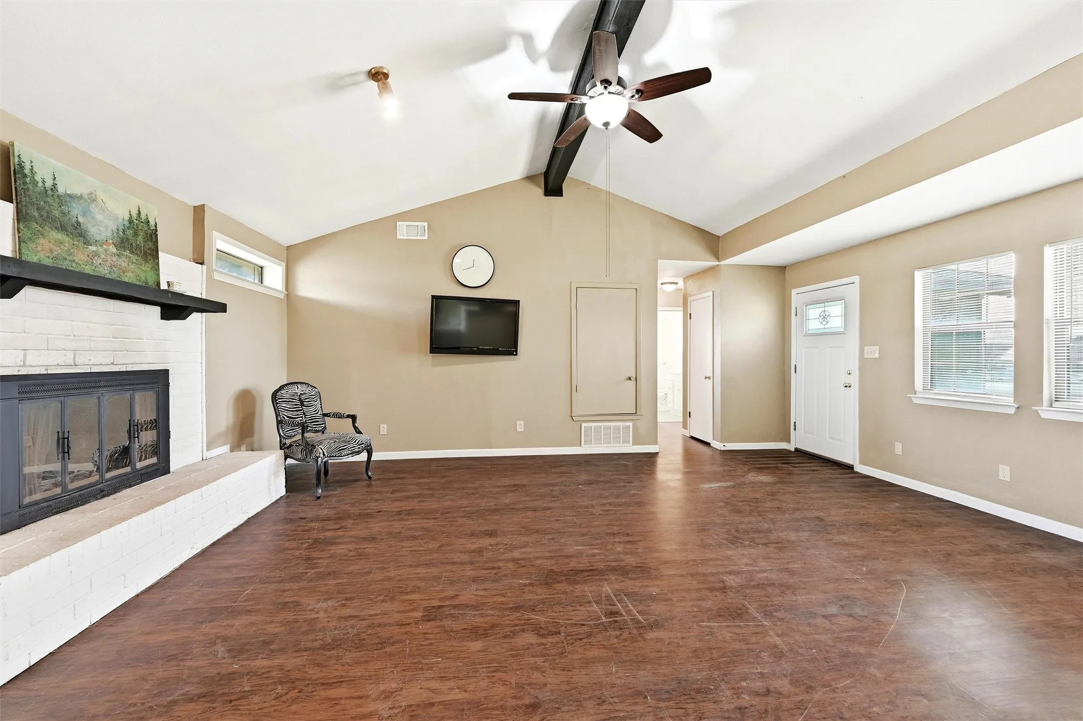 Unfurnished living room featuring plenty of natural light, a fireplace, ceiling fan, and dark wood-type flooring