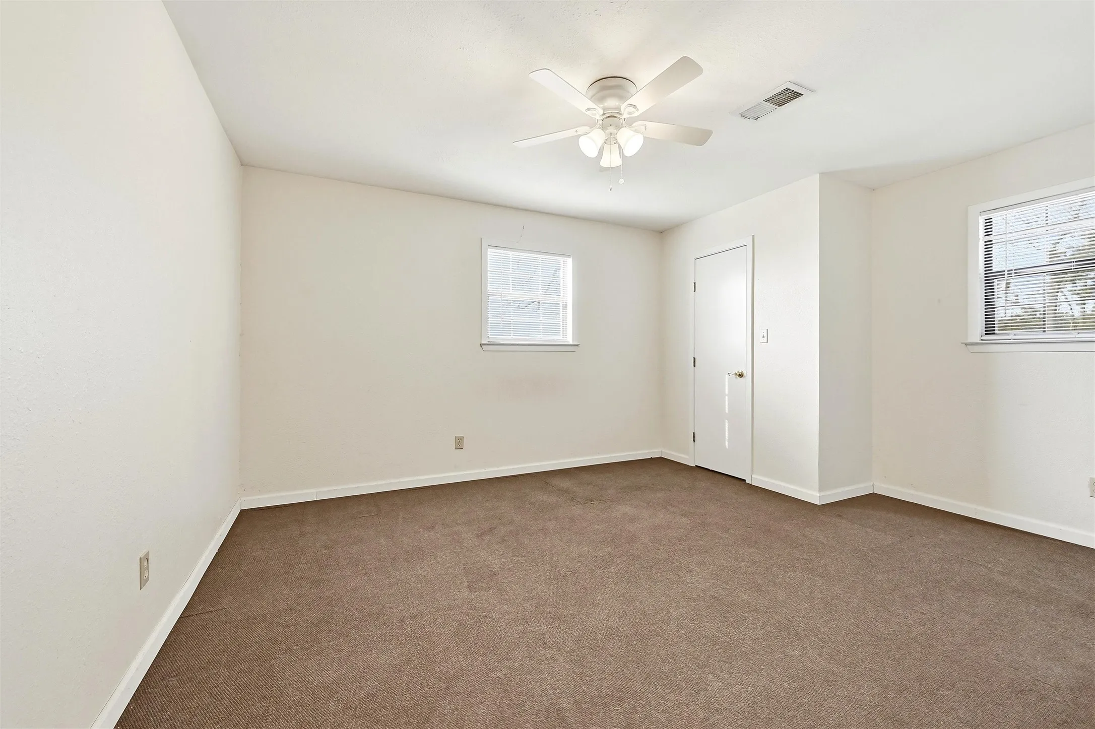 Carpeted spare room featuring baseboards and a ceiling fan