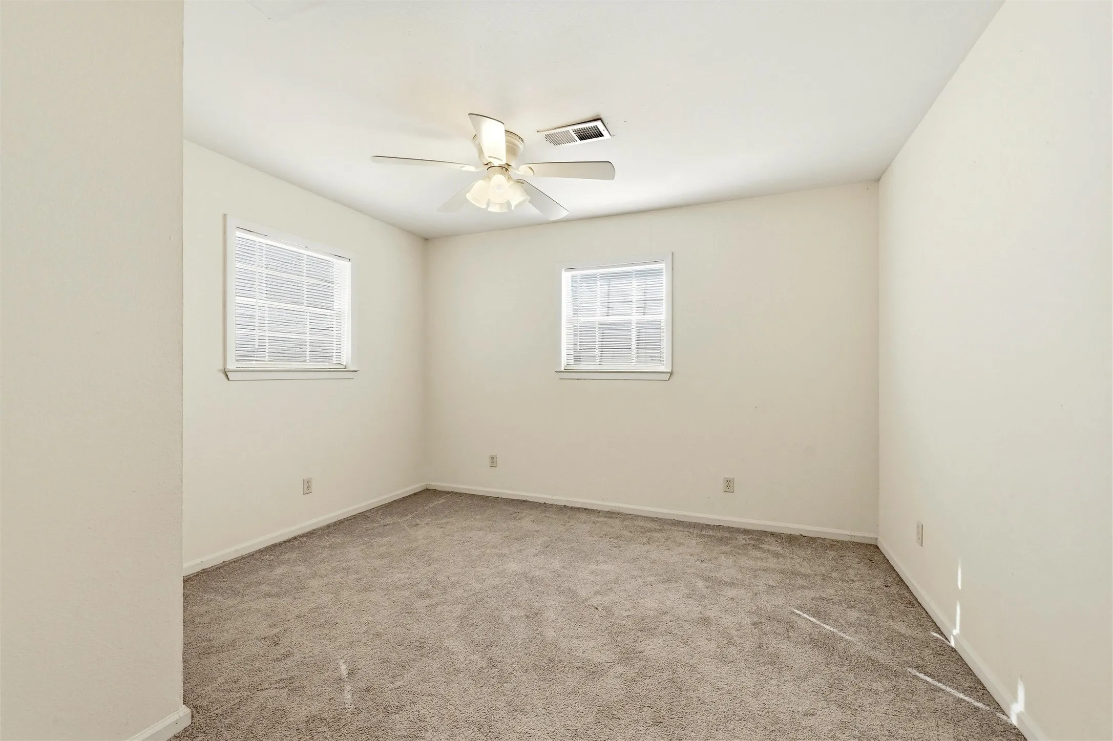 Spare room featuring light carpet and ceiling fan