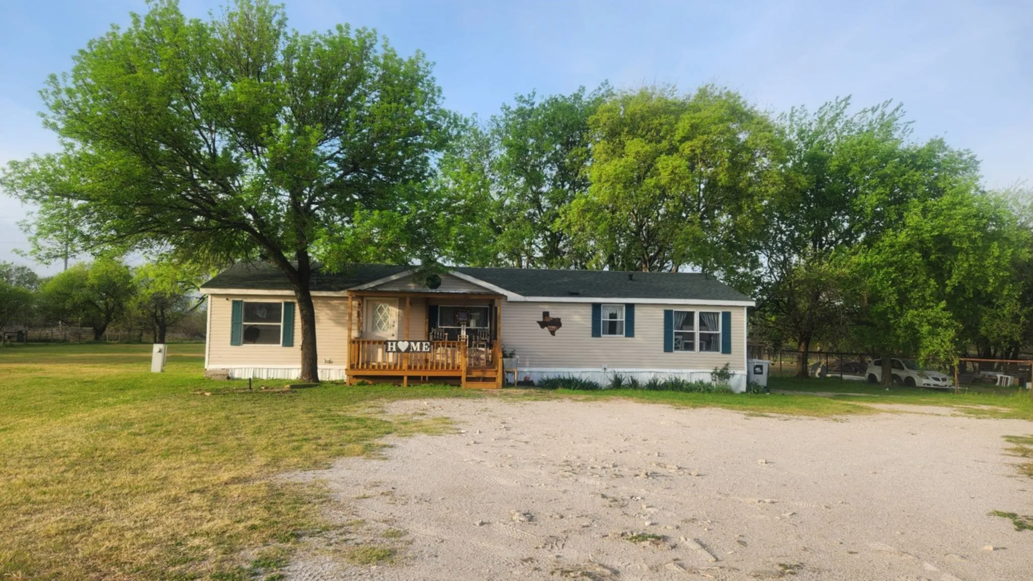 Manufactured / mobile home with a wooden deck, a front yard, and driveway