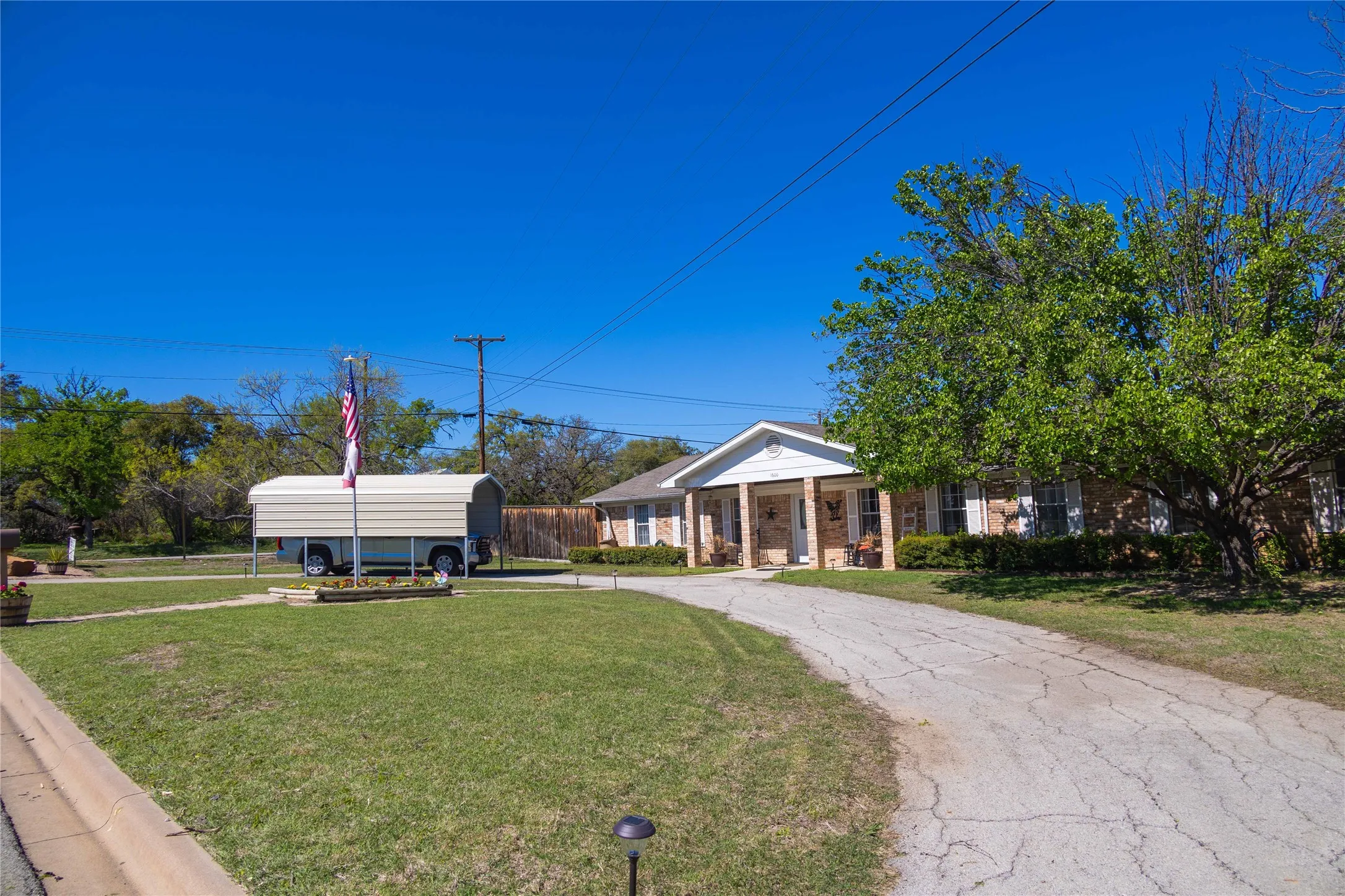 Neoclassical home with a front lawn, aphalt driveway, and a detached carport