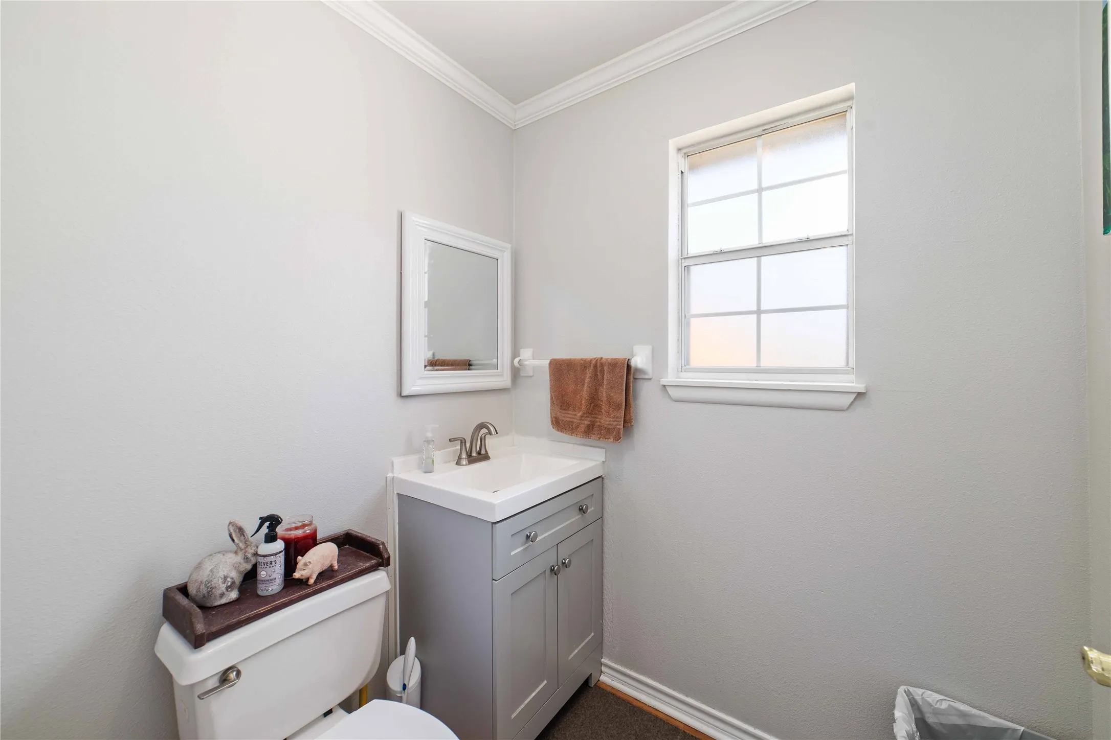 Half bathroom with toilet, crown molding, vanity, and baseboards