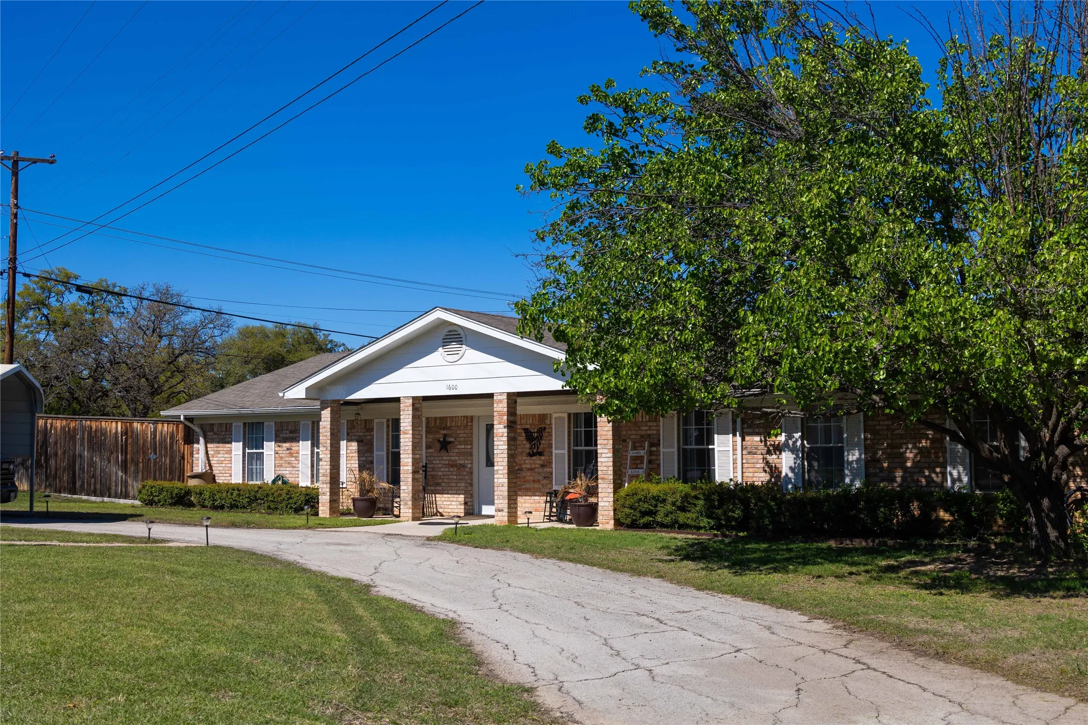Greek revival inspired property featuring brick siding, a porch, and a front yard
