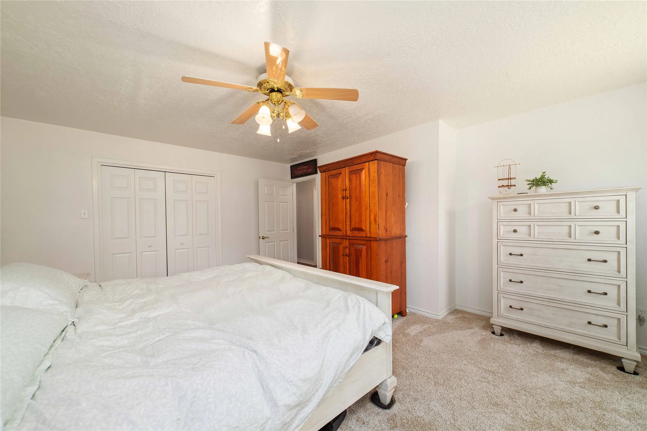Bedroom featuring a ceiling fan, a closet, baseboards, a textured ceiling, and light colored carpet