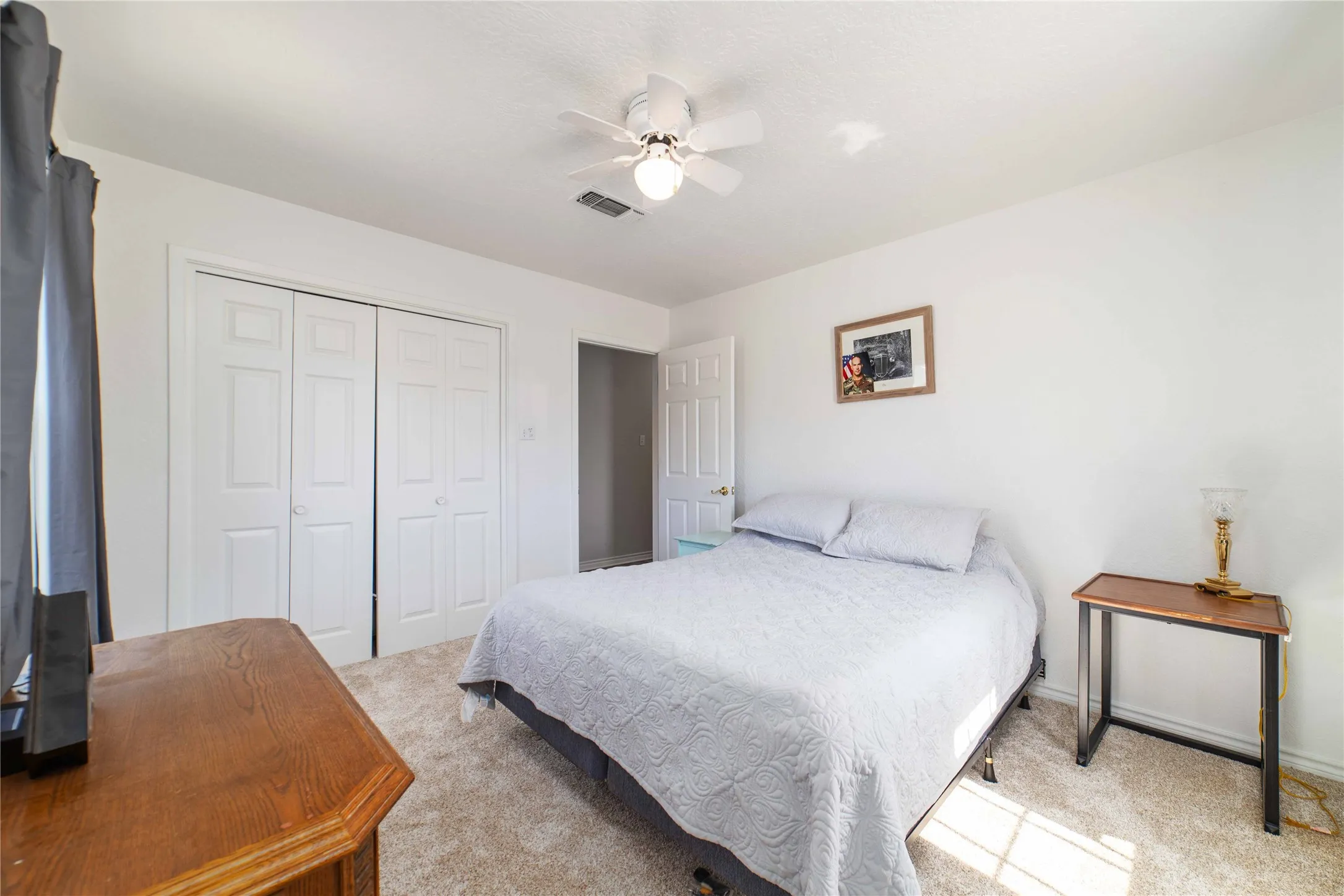 Bedroom featuring carpet floors, a ceiling fan, visible vents, and a closet