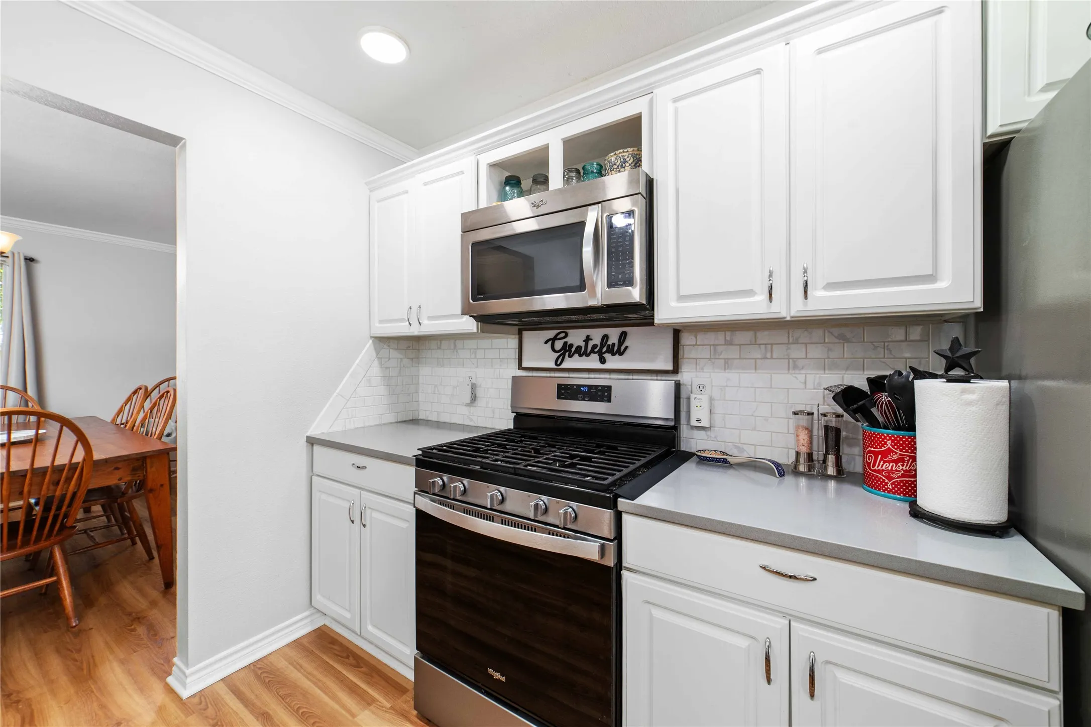 Kitchen featuring appliances with stainless steel finishes, crown molding, light countertops, and light wood-style floors