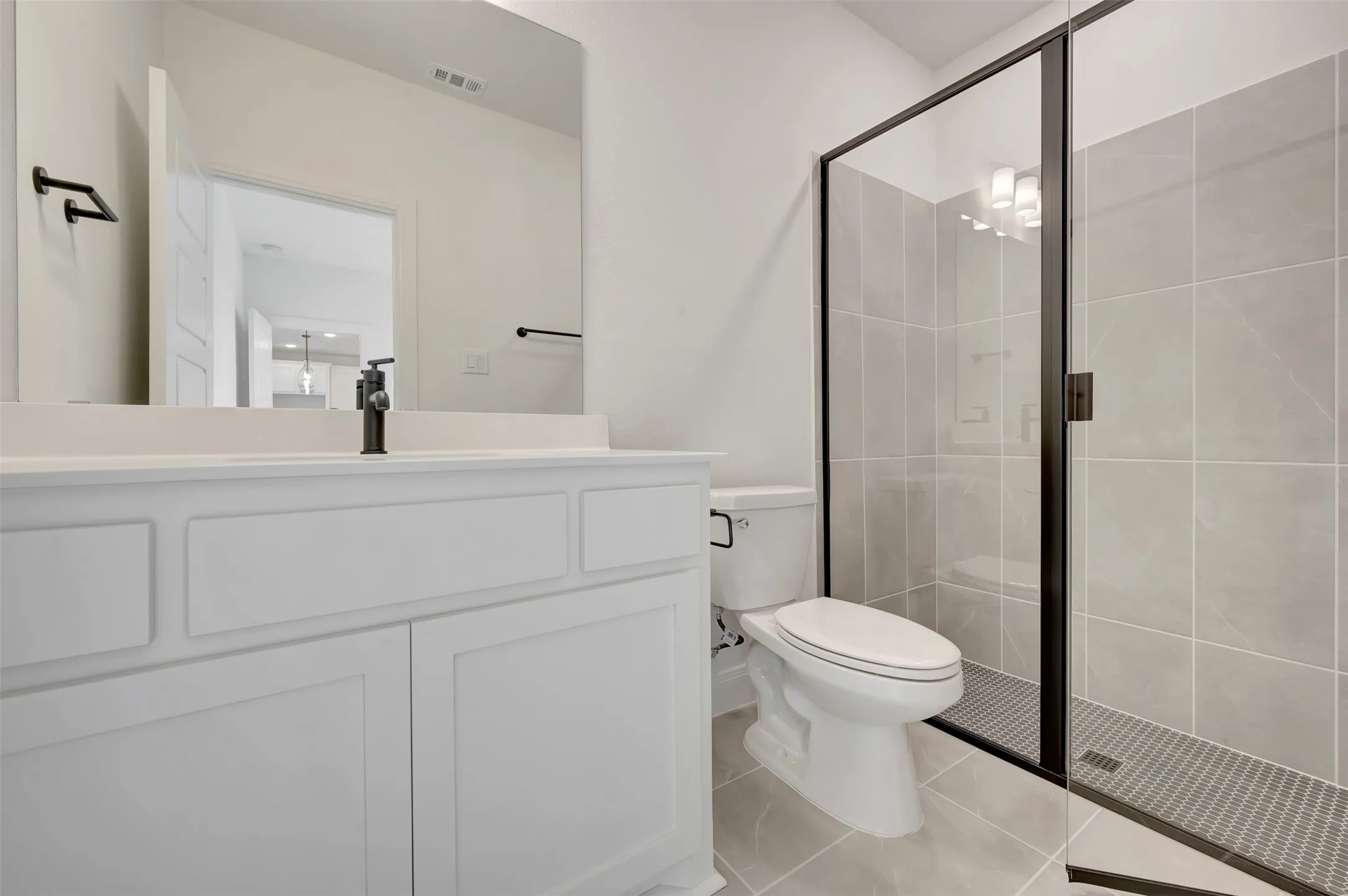 Full bath featuring vanity, a stall shower, and light tile patterned floors