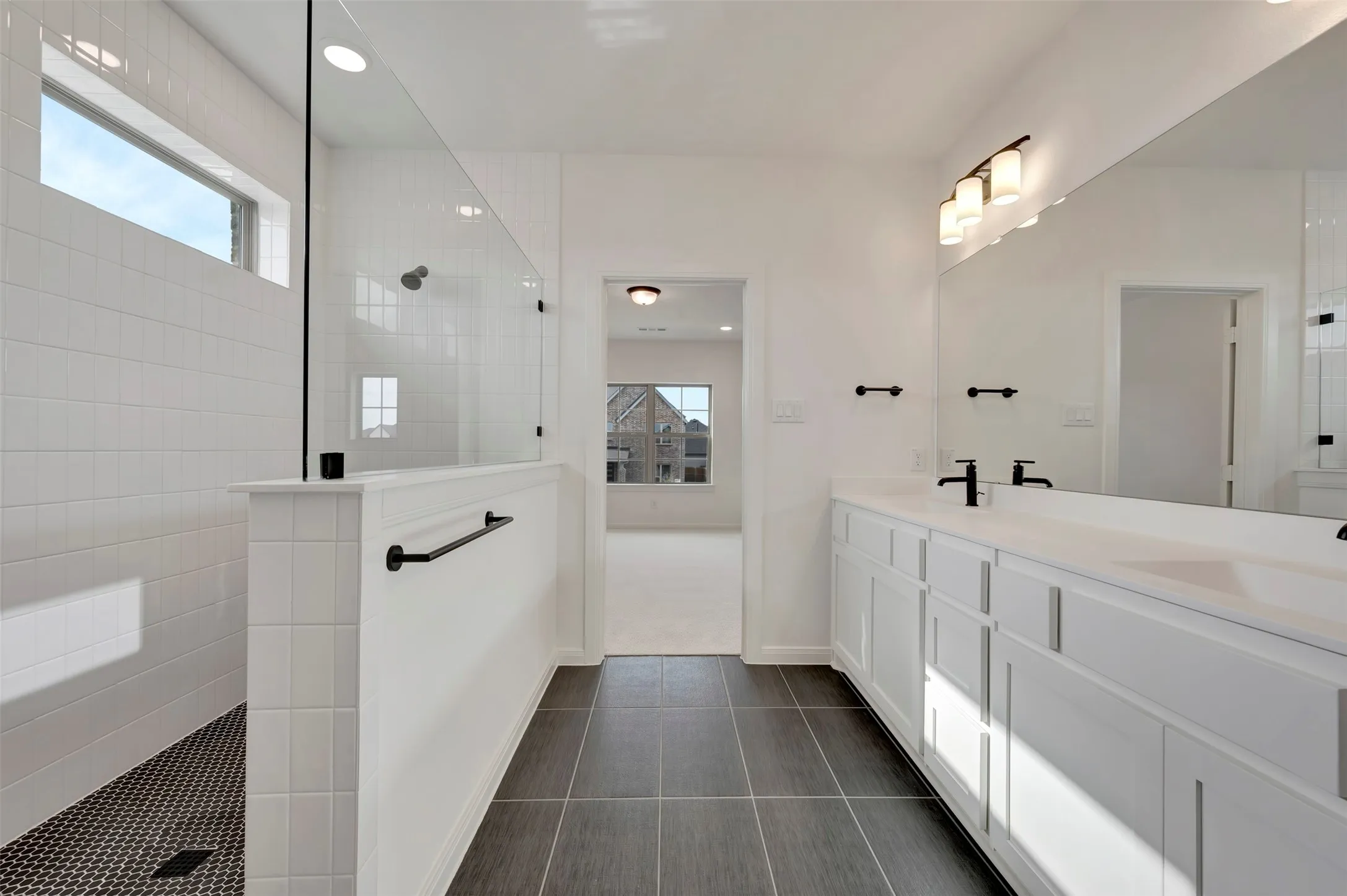Full bath with walk in shower, double vanity, recessed lighting, and dark tile patterned floors