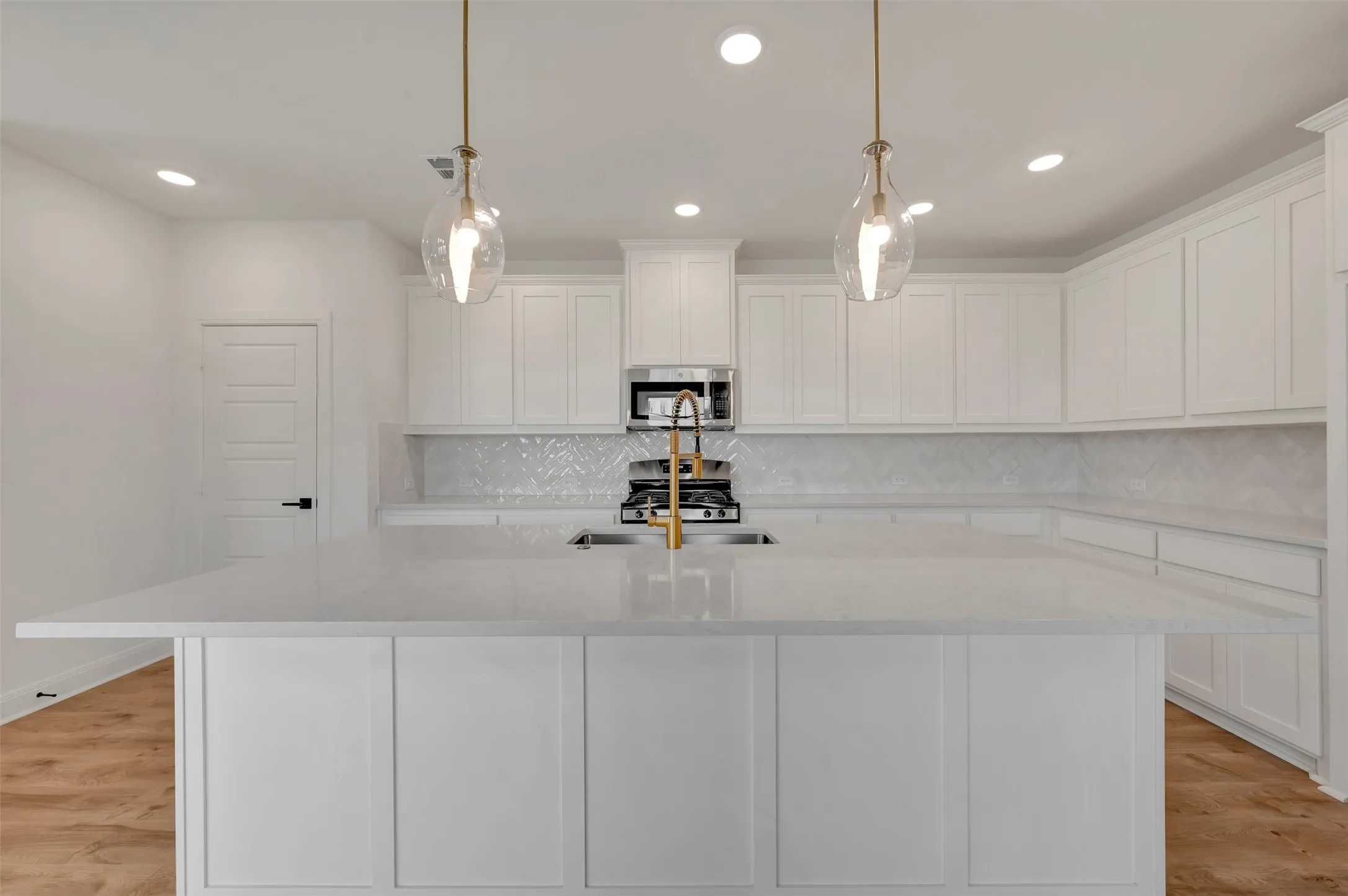 Kitchen with light wood-style flooring, white cabinetry, light stone counters, and stainless steel appliances