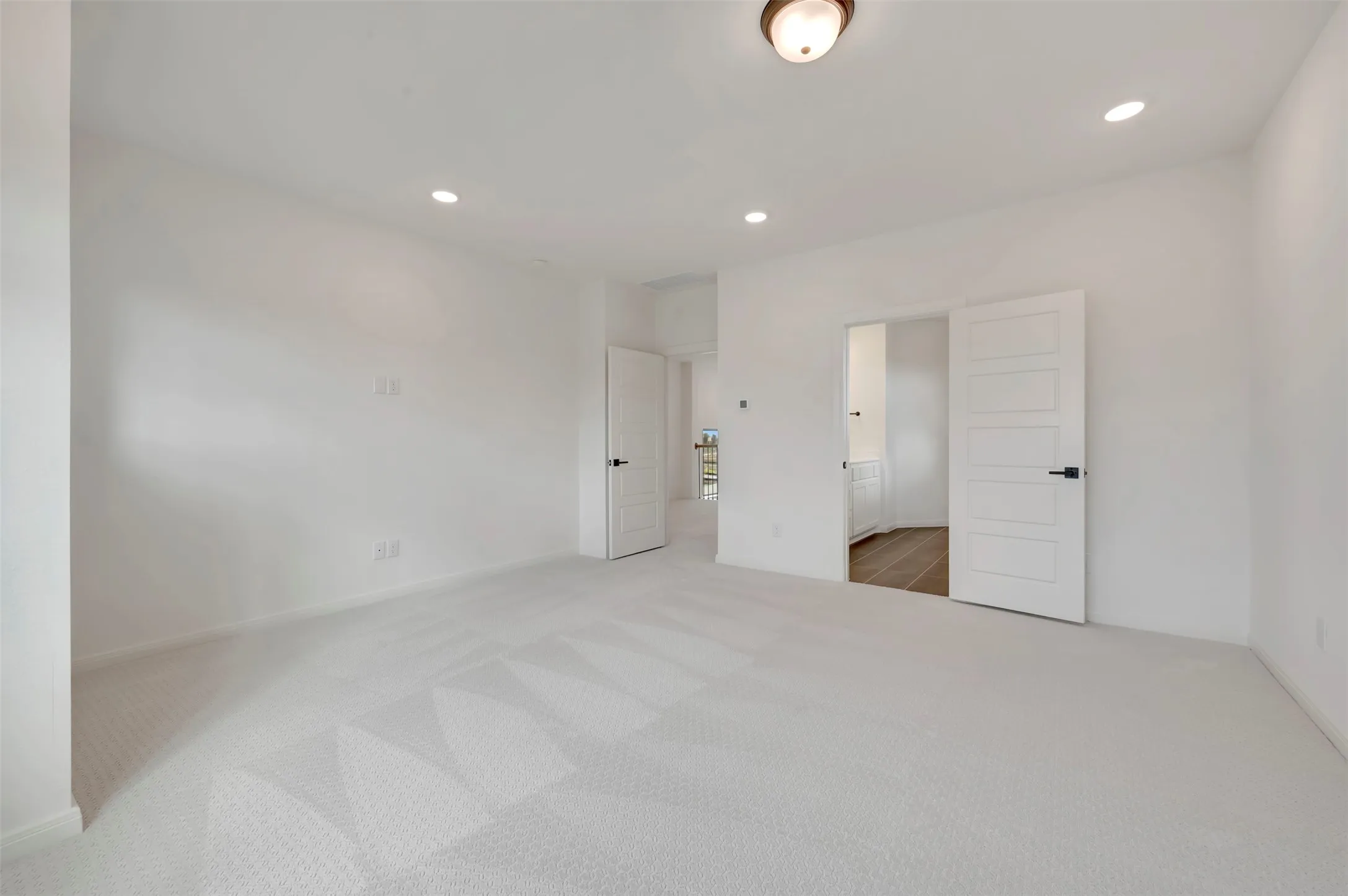 Unfurnished bedroom featuring recessed lighting, light colored carpet, and ensuite bathroom