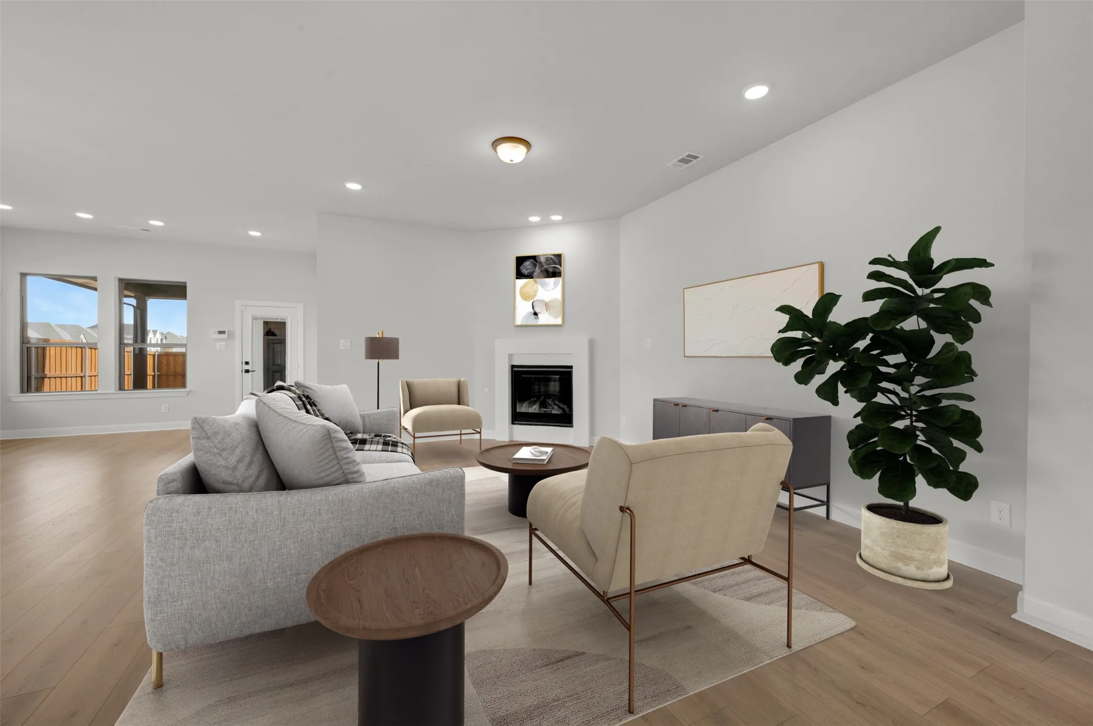 Living room featuring light wood finished floors, a glass covered fireplace, and recessed lighting