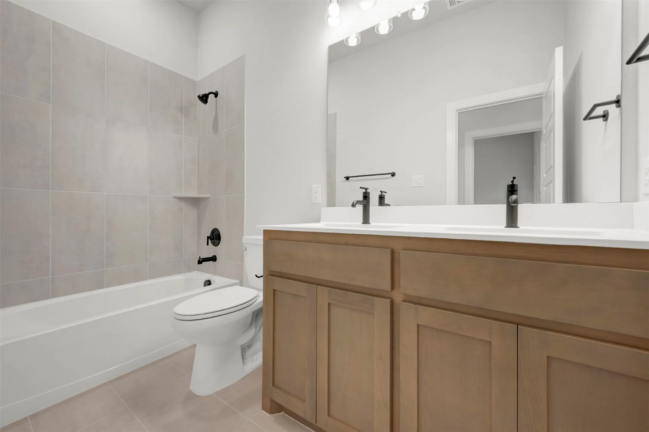Full bathroom with double vanity, shower / tub combination, and light tile patterned flooring