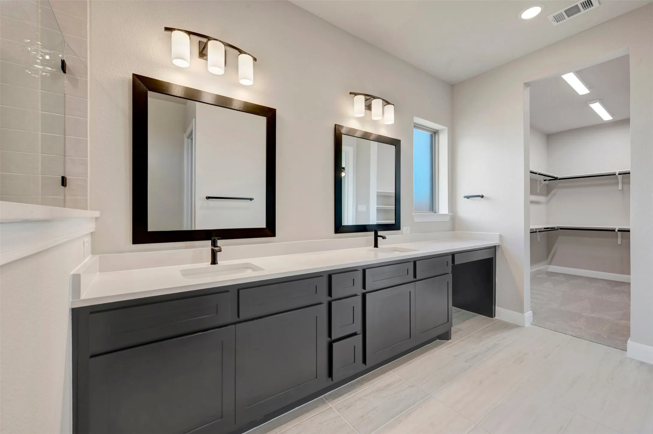 Dual vanity featuring quartz countertops, dark cabinetry, and black fixtures