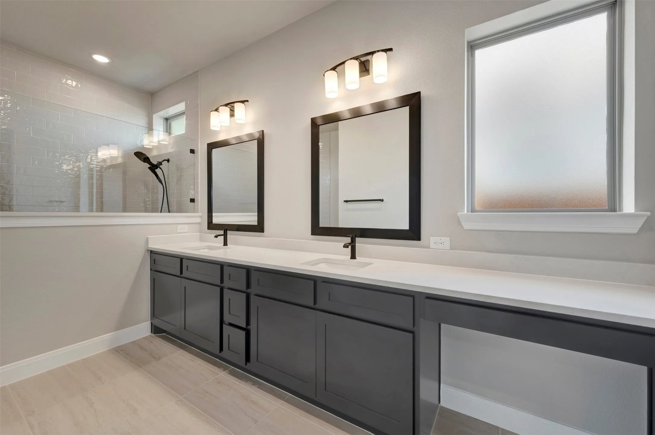 Dual vanity with dark cabinetry, white countertops, and matte black fixtures