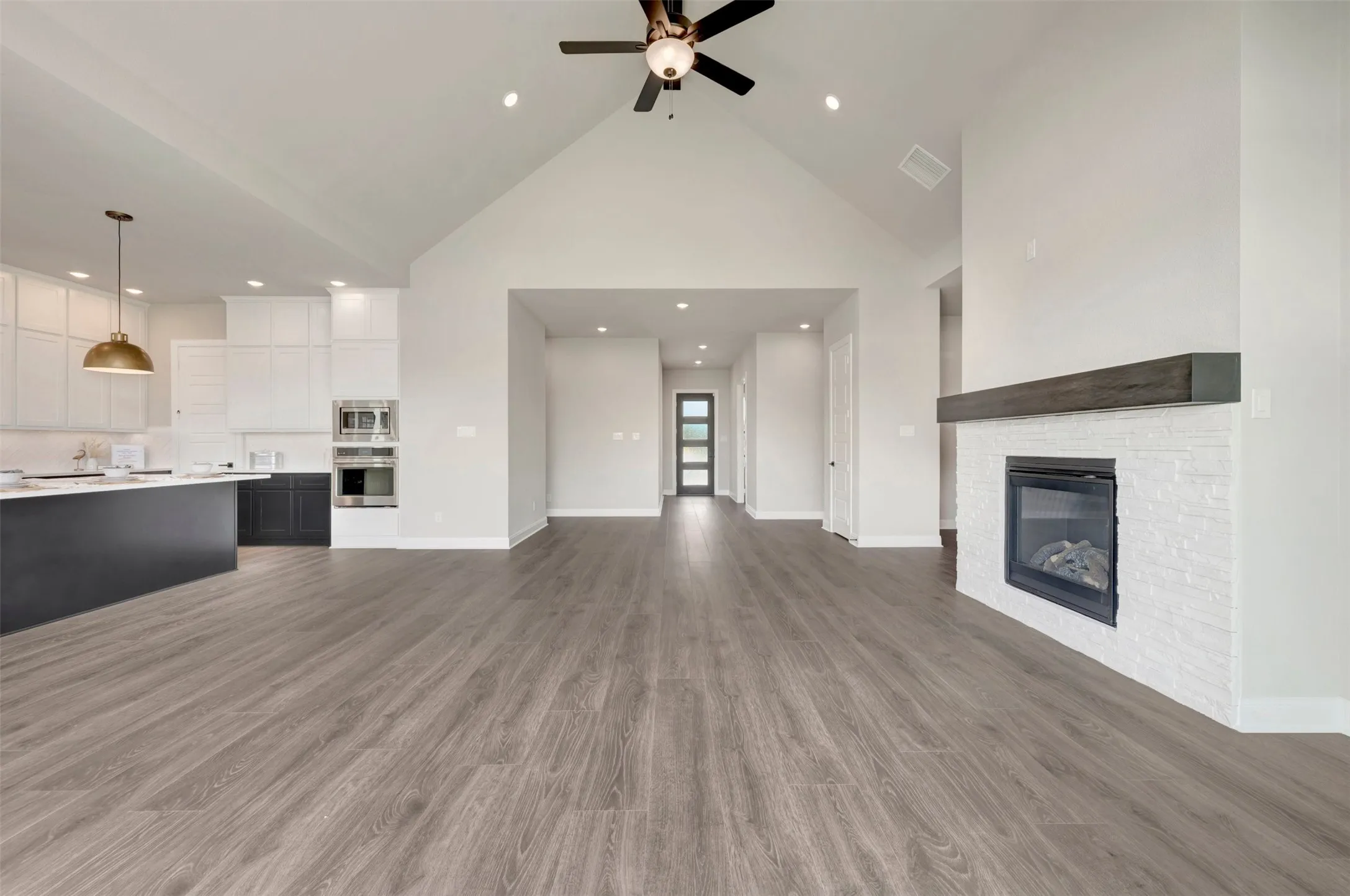 Open-concept living space with vaulted ceilings, wood-finish flooring, and recessed lighting