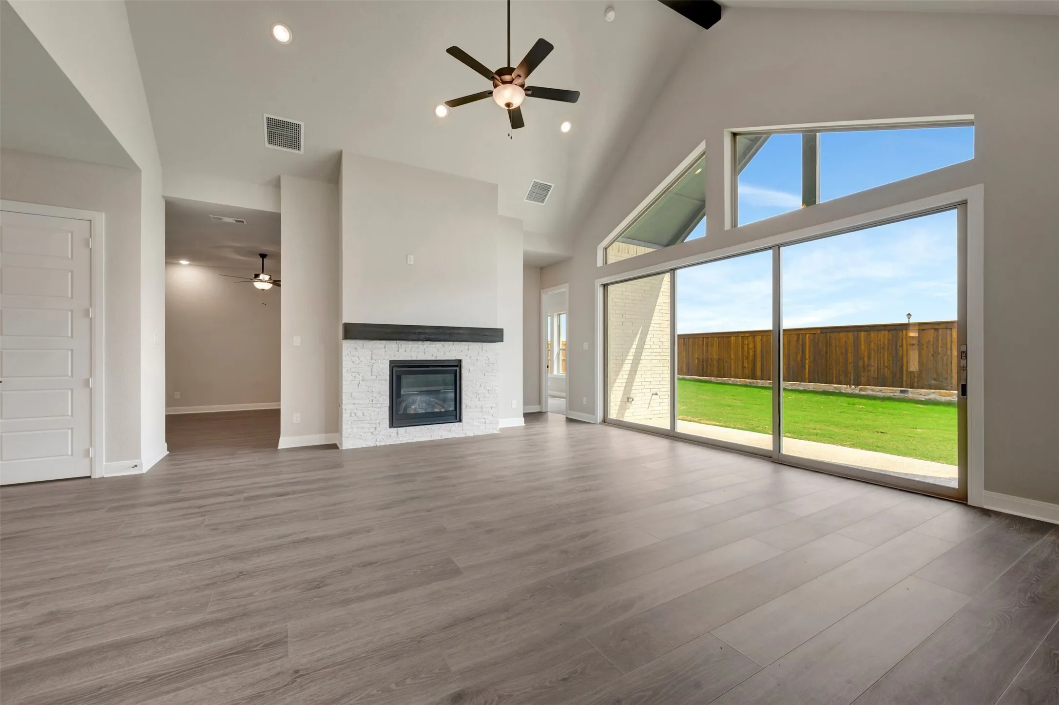 Spacious living area featuring a vaulted ceiling with exposed beams, an integrated ceiling fan, and recessed lighting