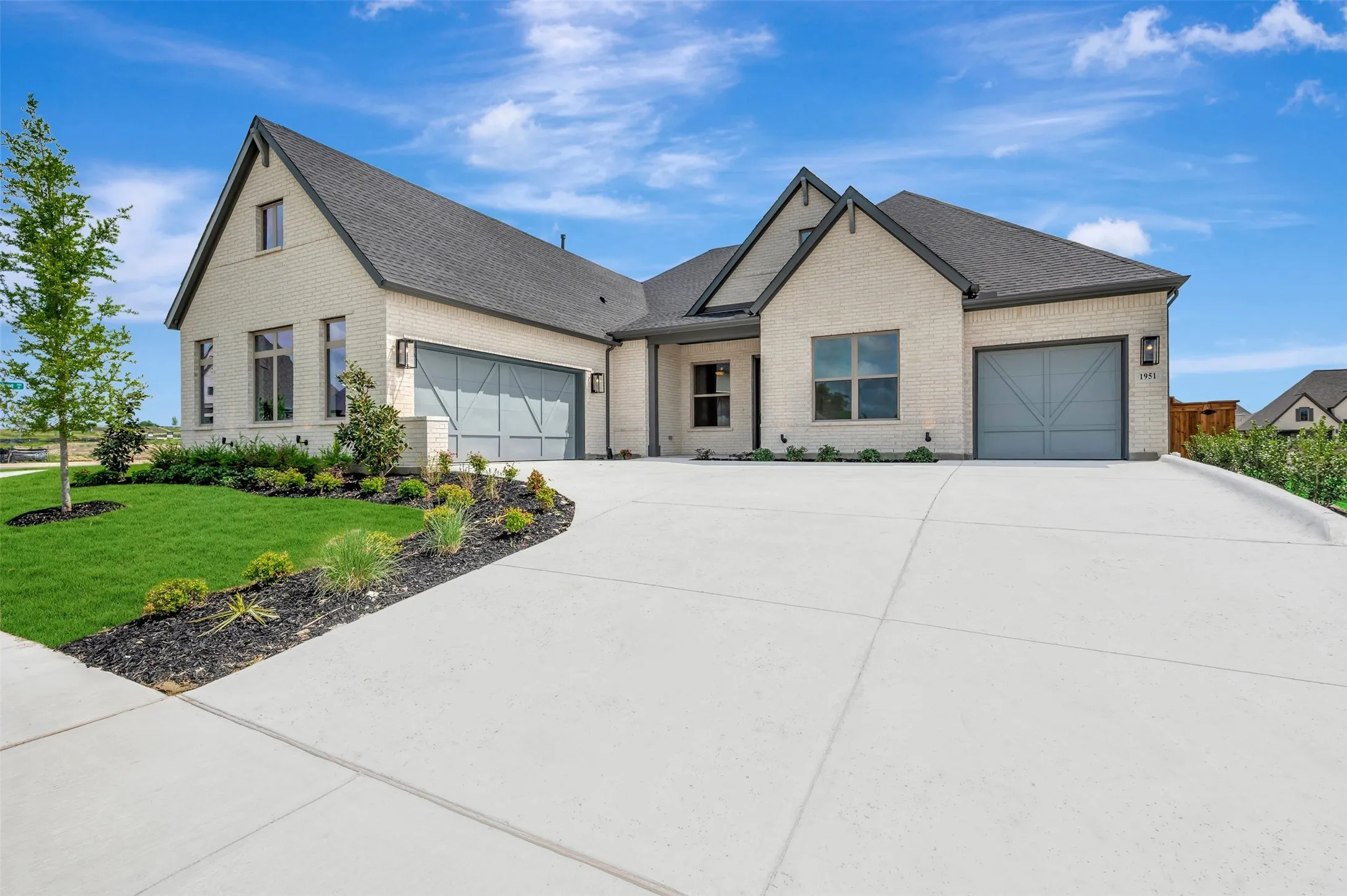 Light brick exterior featuring a dark asphalt shingle roof, two distinct gables, and a concrete driveway