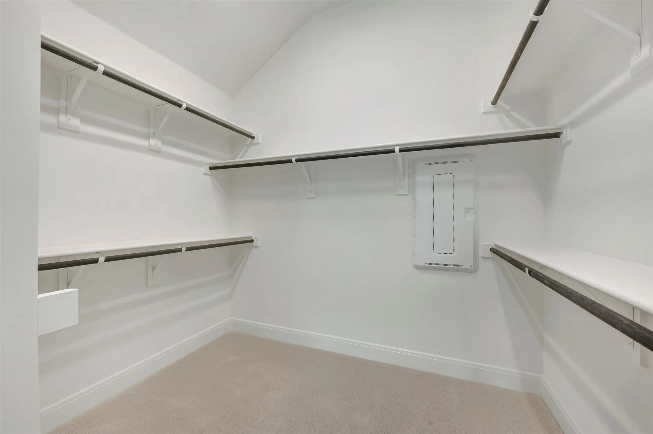 Spacious walk-in closet featuring white shelving and dark-finished hanging rods