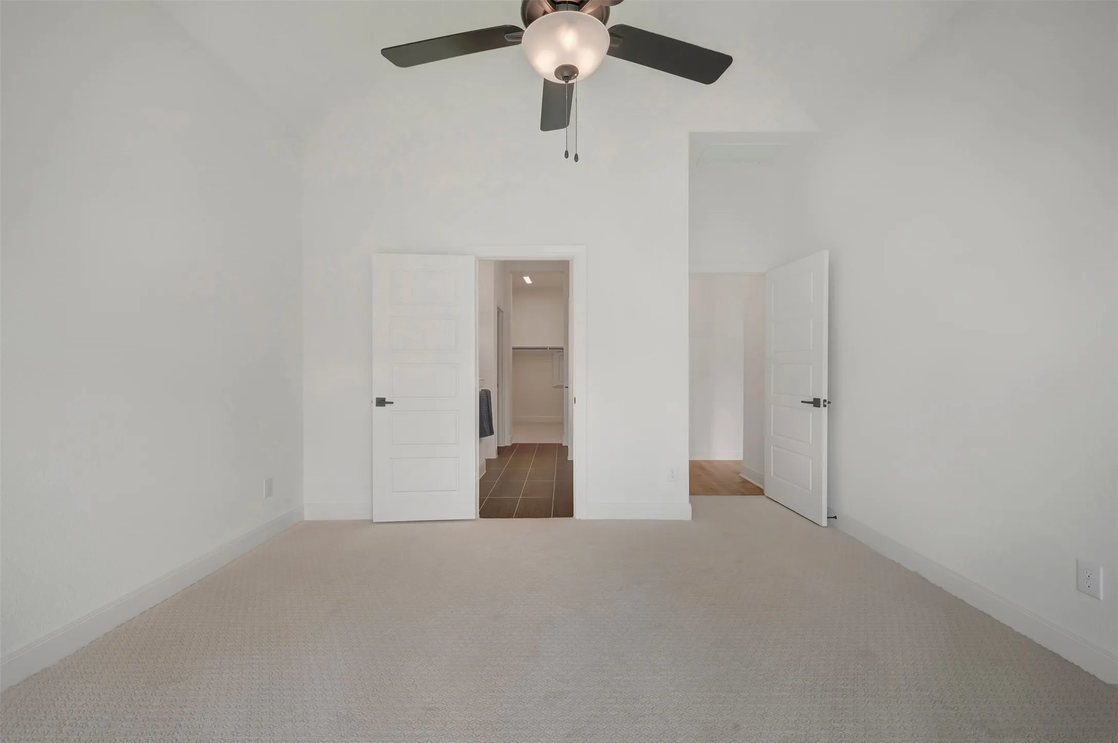 Carpeted room with a vaulted ceiling and a ceiling fan with integrated lighting
