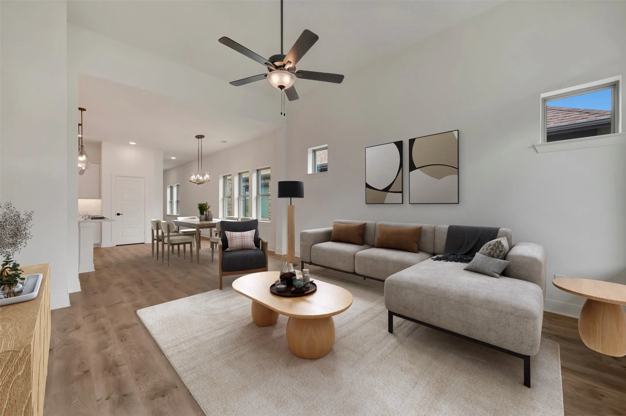 Spacious living area featuring a ceiling fan, wood-finish flooring, and high ceilings