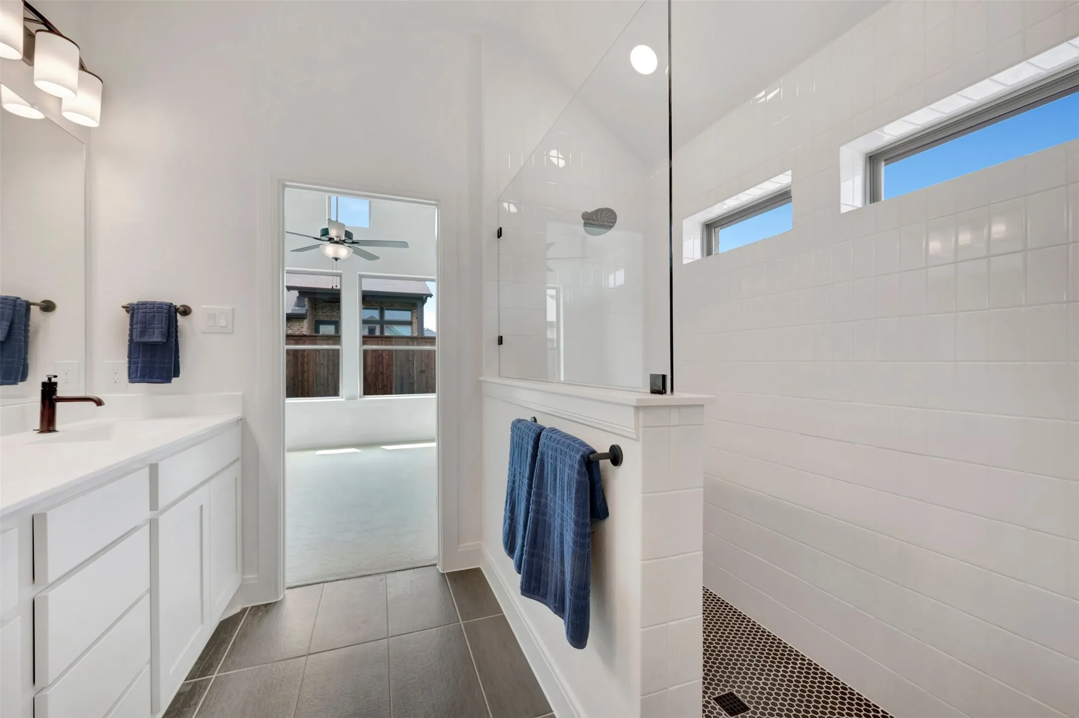 Contemporary bathroom featuring a glass-enclosed shower with white subway tile walls and a dark penny tile floor