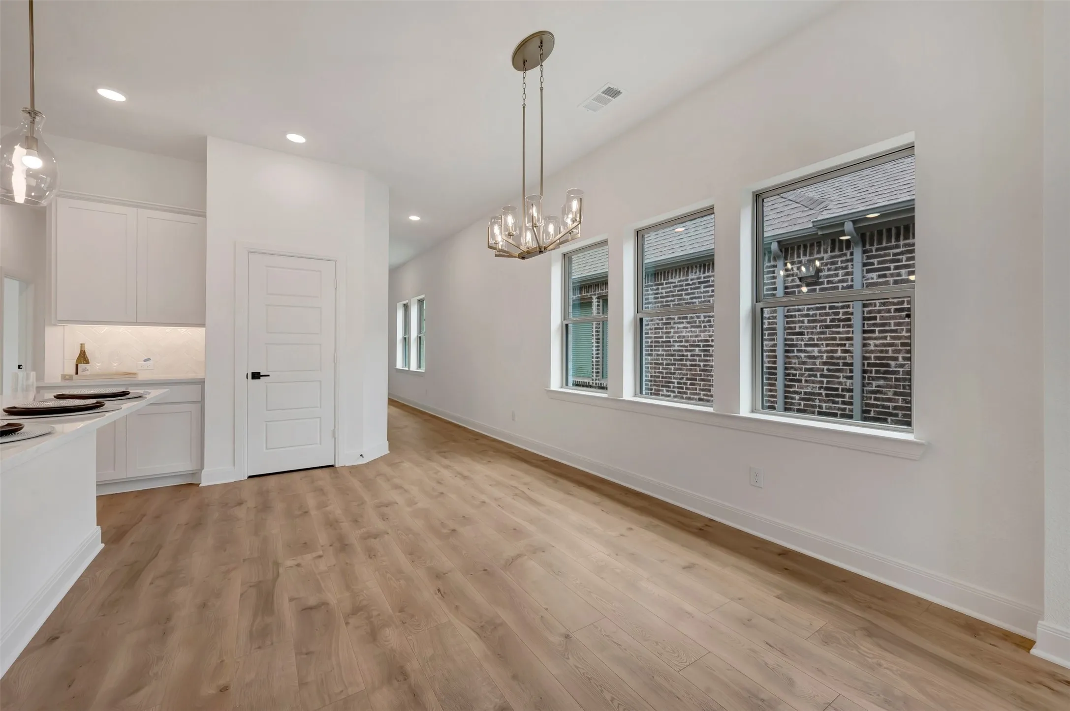 Open-concept living area with wood-finish flooring, white walls, and recessed lighting