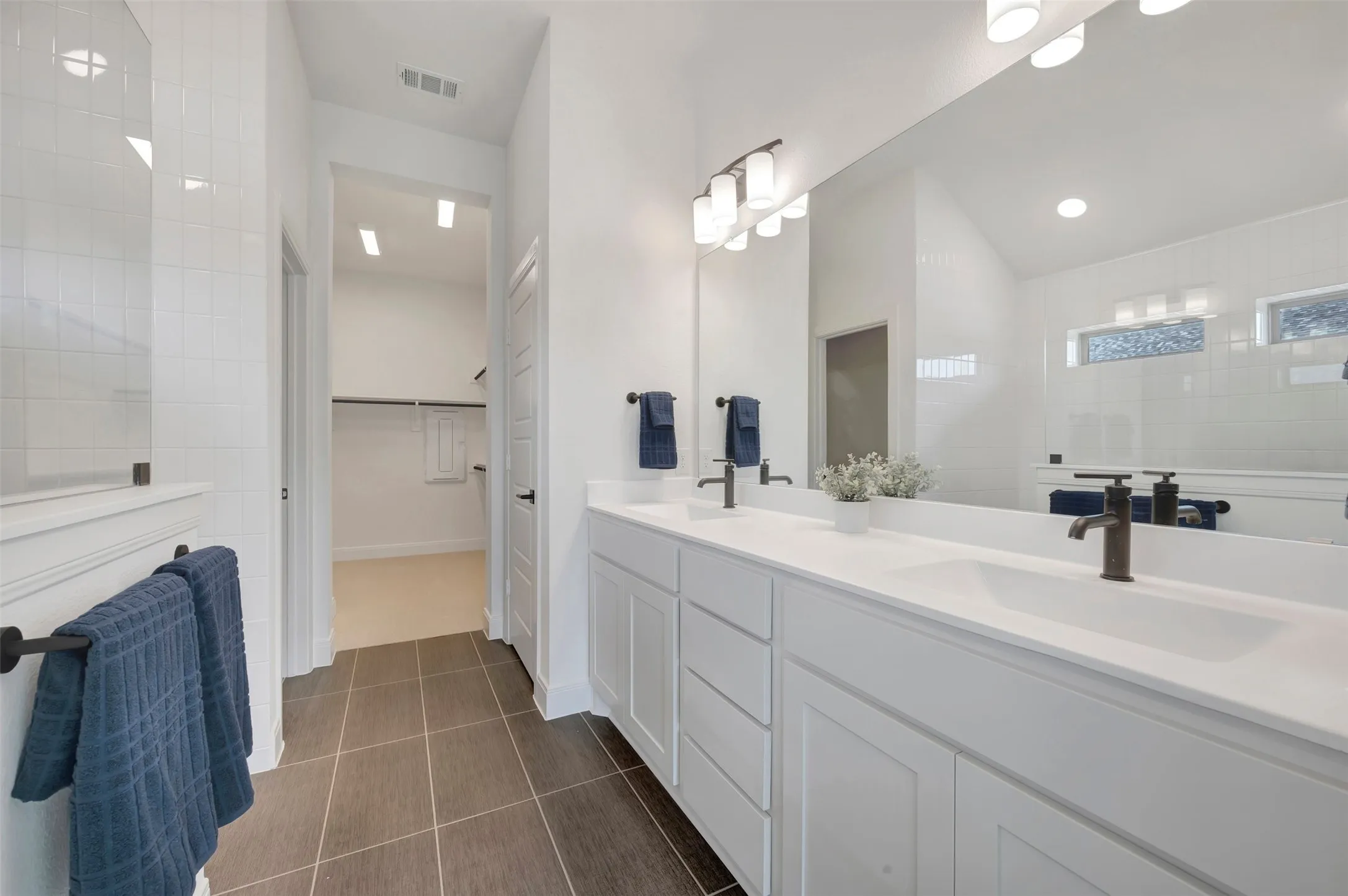 Spacious bathroom featuring a dual vanity with white cabinetry and integrated sinks