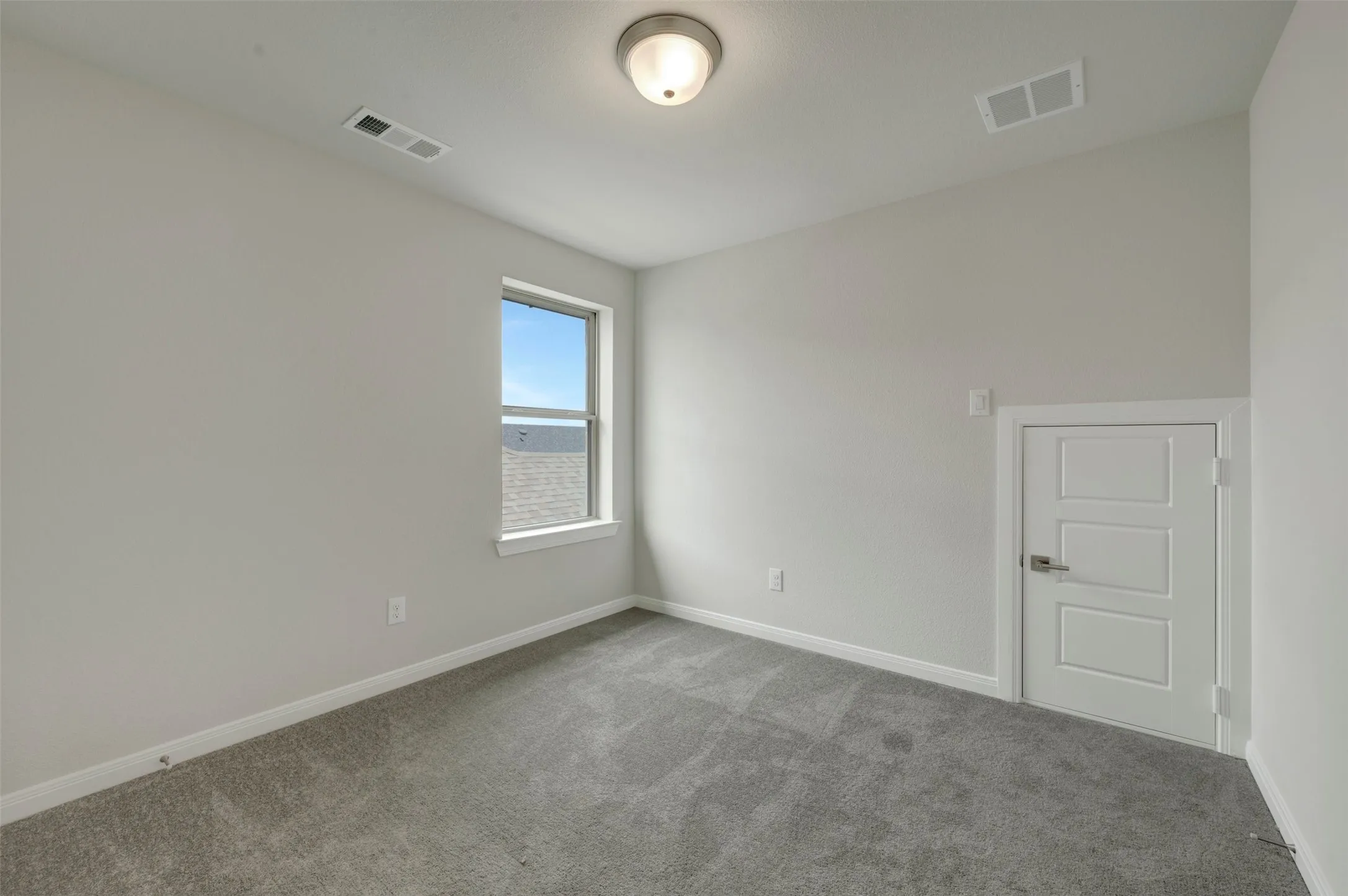 Carpeted room with a single window and a white paneled door