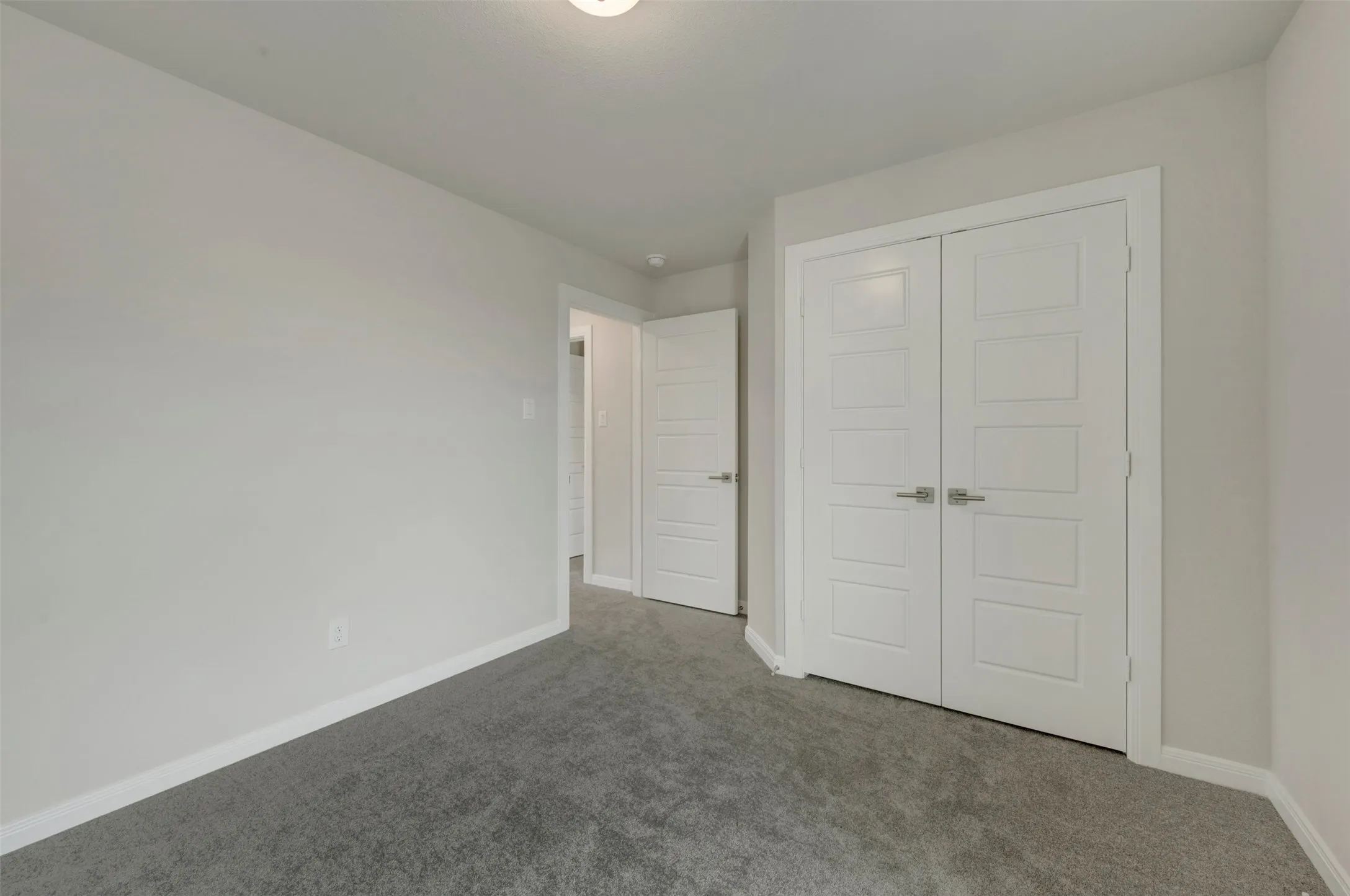 Interior room featuring plush gray carpeting, light-toned wall paint, and white baseboards