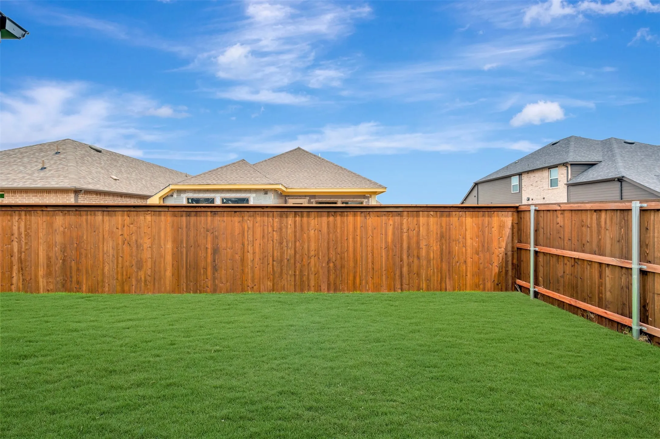 Expansive backyard featuring a lush green lawn and a new wood privacy fence
