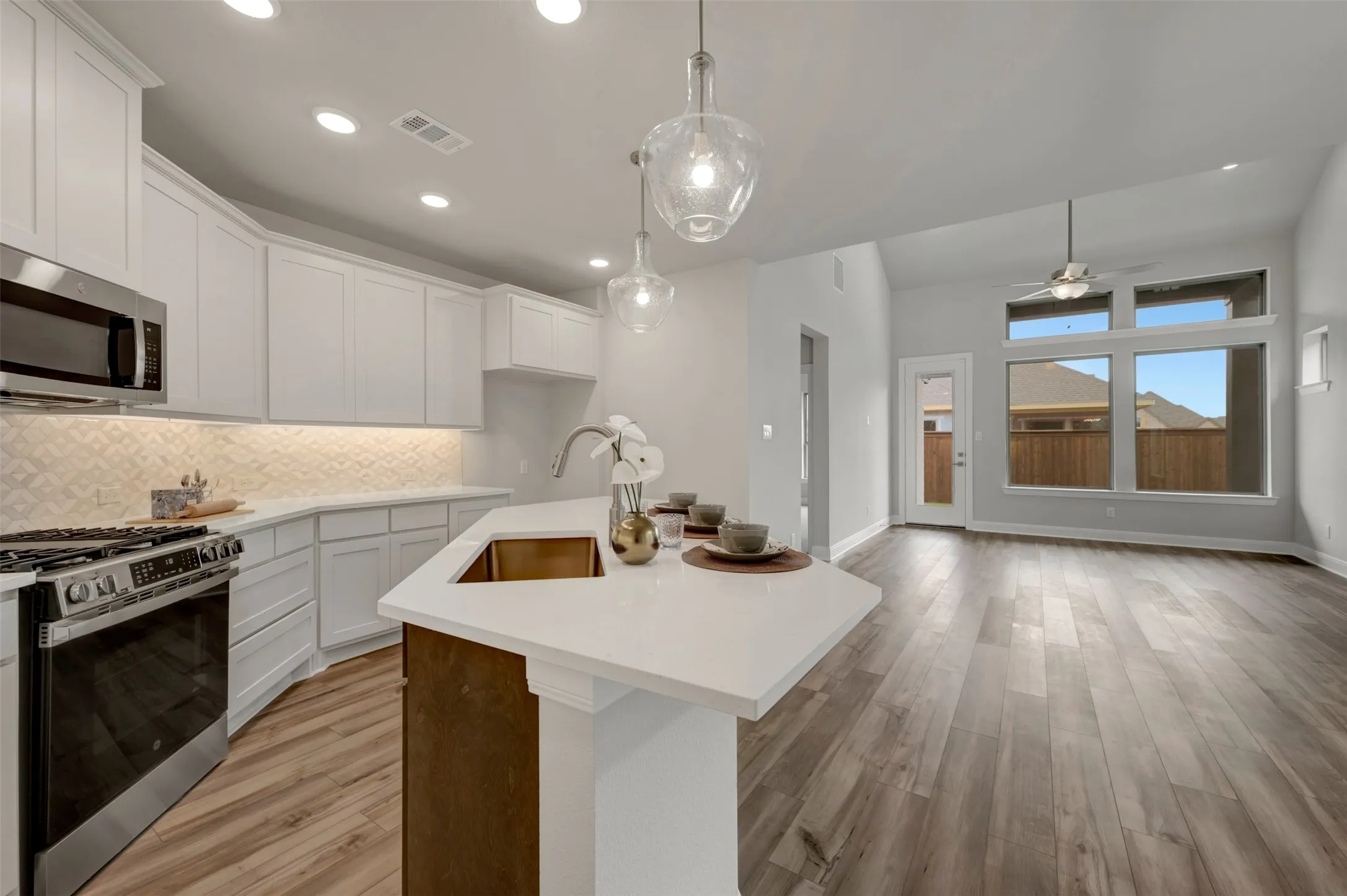 Kitchen island with a copper-tone sink, white countertops, and pendant lighting