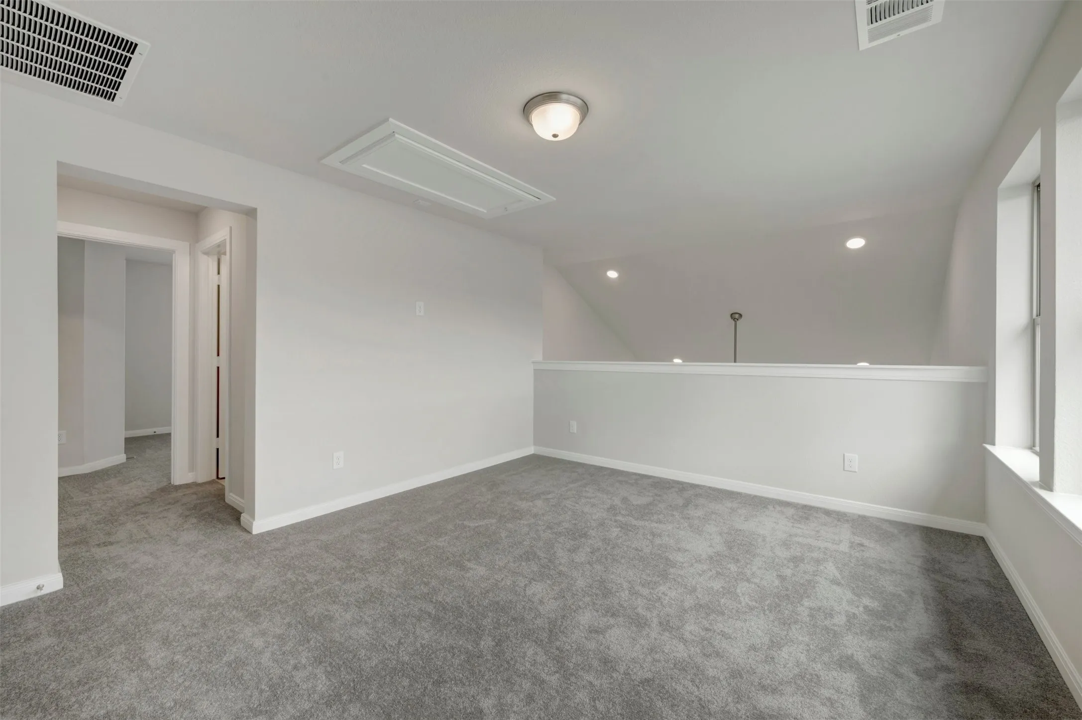 Carpeted loft space featuring light gray walls, white trim, a semi-flush mount ceiling fixture, and recessed lighting